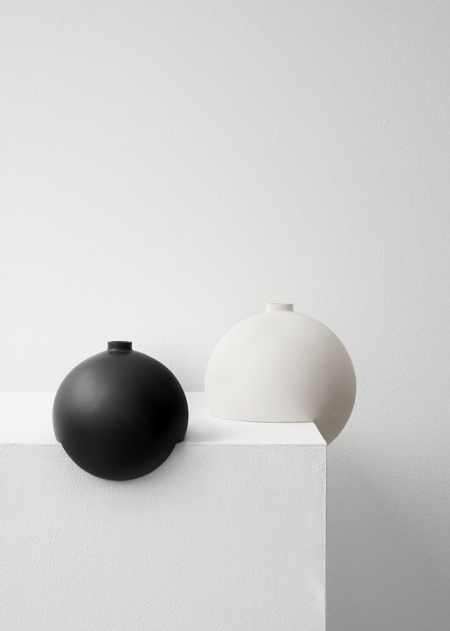 Tumble by Falke Svatun — Two slip-cast stoneware vessels with matte finish positioned on a white plaster platform.