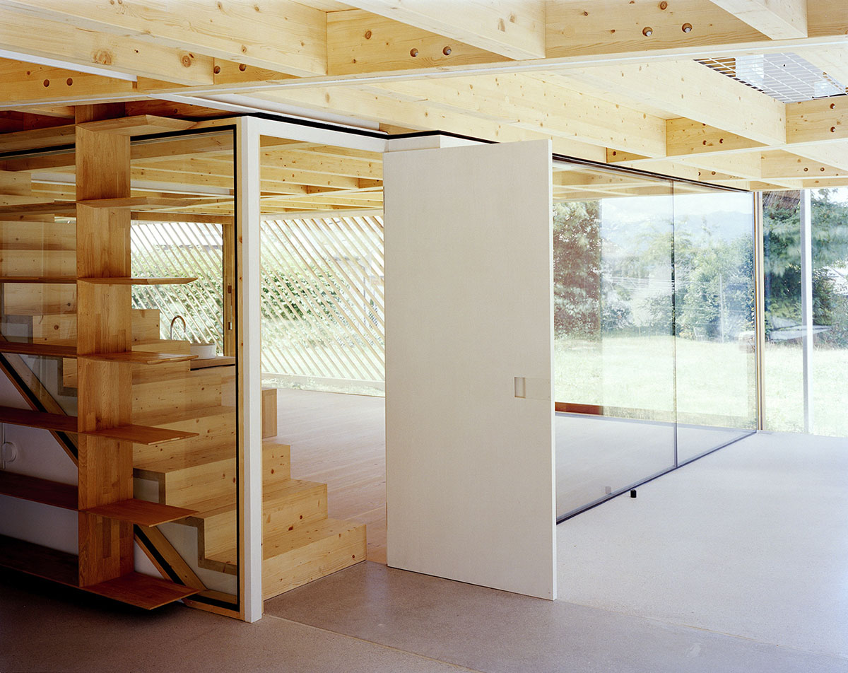 2 Houses in Chigny by Dieterdietz.org — Interior passage featuring a monolithic white plaster partition wall that divides shared and individual living zones.