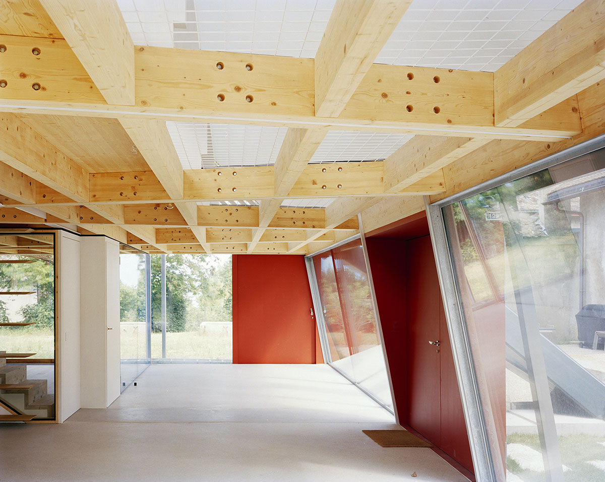 2 Houses in Chigny by Dieterdietz.org — Interior of the new structure revealing the post-and-beam construction system with exposed pine timber frame and white-painted steel cross-bracing.