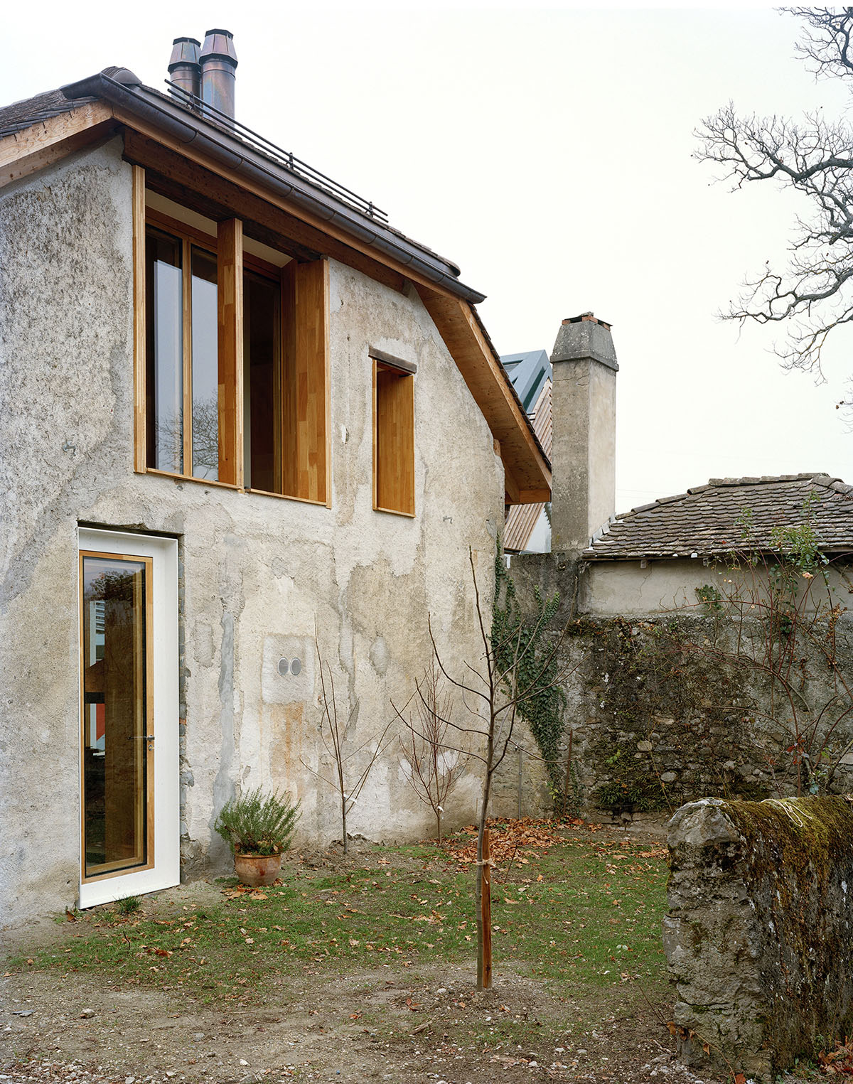 2 Houses in Chigny by Dieterdietz.org — A rendered stone wall with visible moss patina and weathered surface forms the backdrop to this courtyard view.