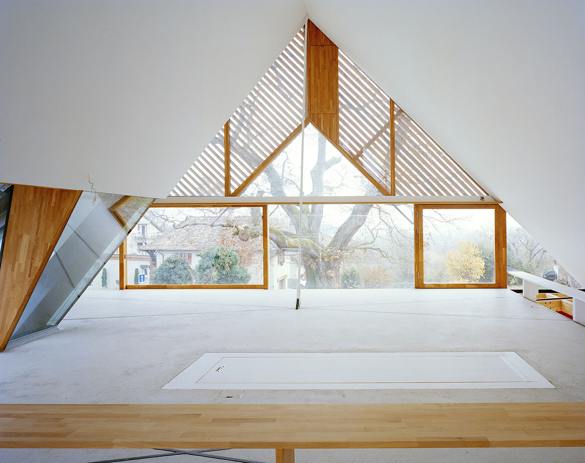 2 Houses in Chigny by Dieterdietz.org — A double-height attic interior with pitched timber roof structure and horizontal wood louvers filtering light across white walls.