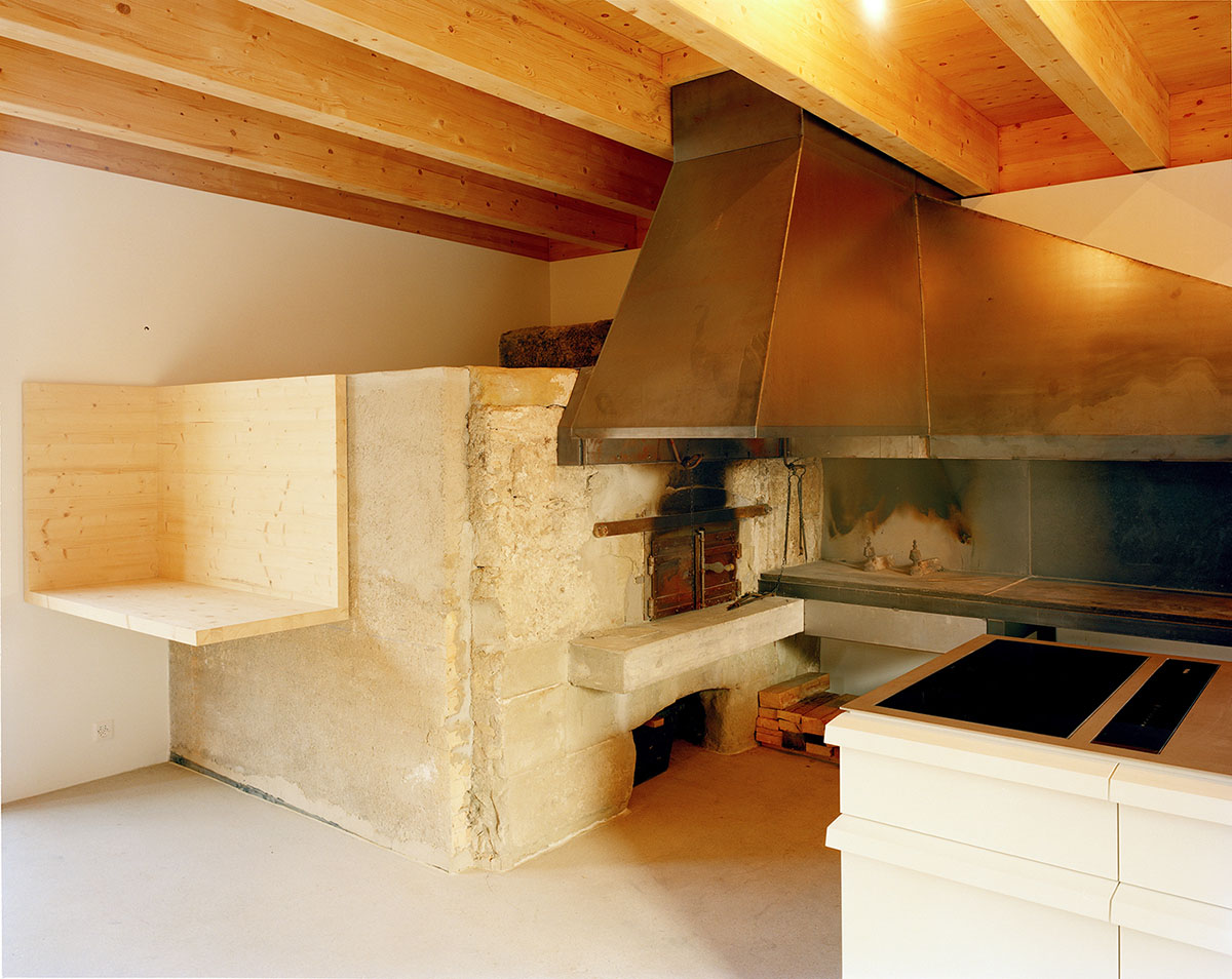 2 Houses in Chigny by Dieterdietz.org — Interior view of a kitchen workspace featuring a monolithic stone mass with board-formed concrete elements.