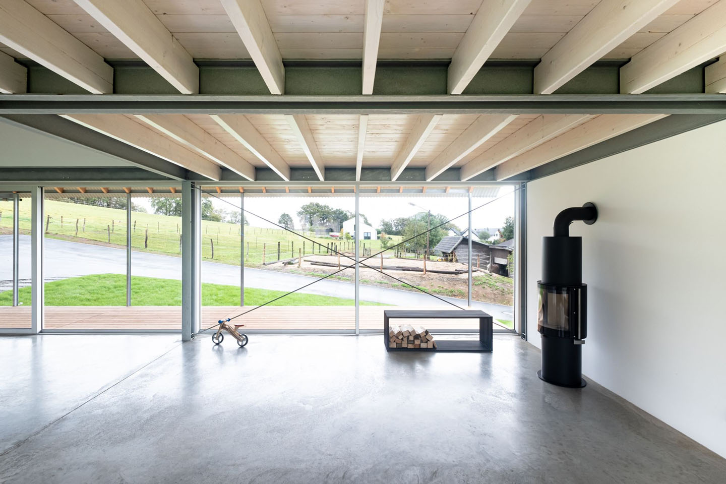 House D6 by Aretz Dürr Architektur — A double-height interior framed by regular timber beams at 5.4-metre intervals, their natural wood grain contrasting with white-painted soffit panels above.