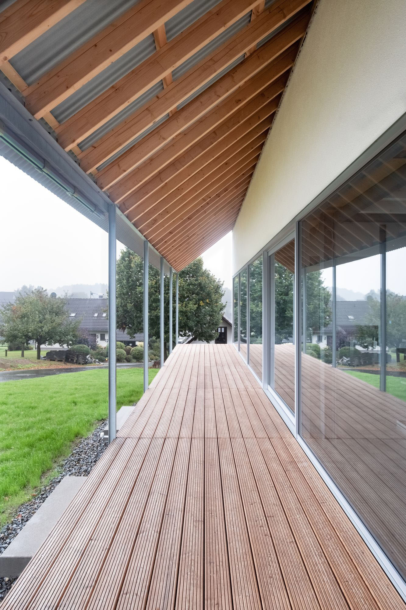 House D6 by Aretz Dürr Architektur — A covered timber deck extends from the modernist dwelling into the landscape, framed by large glazed sliding doors that dissolve the threshold between...