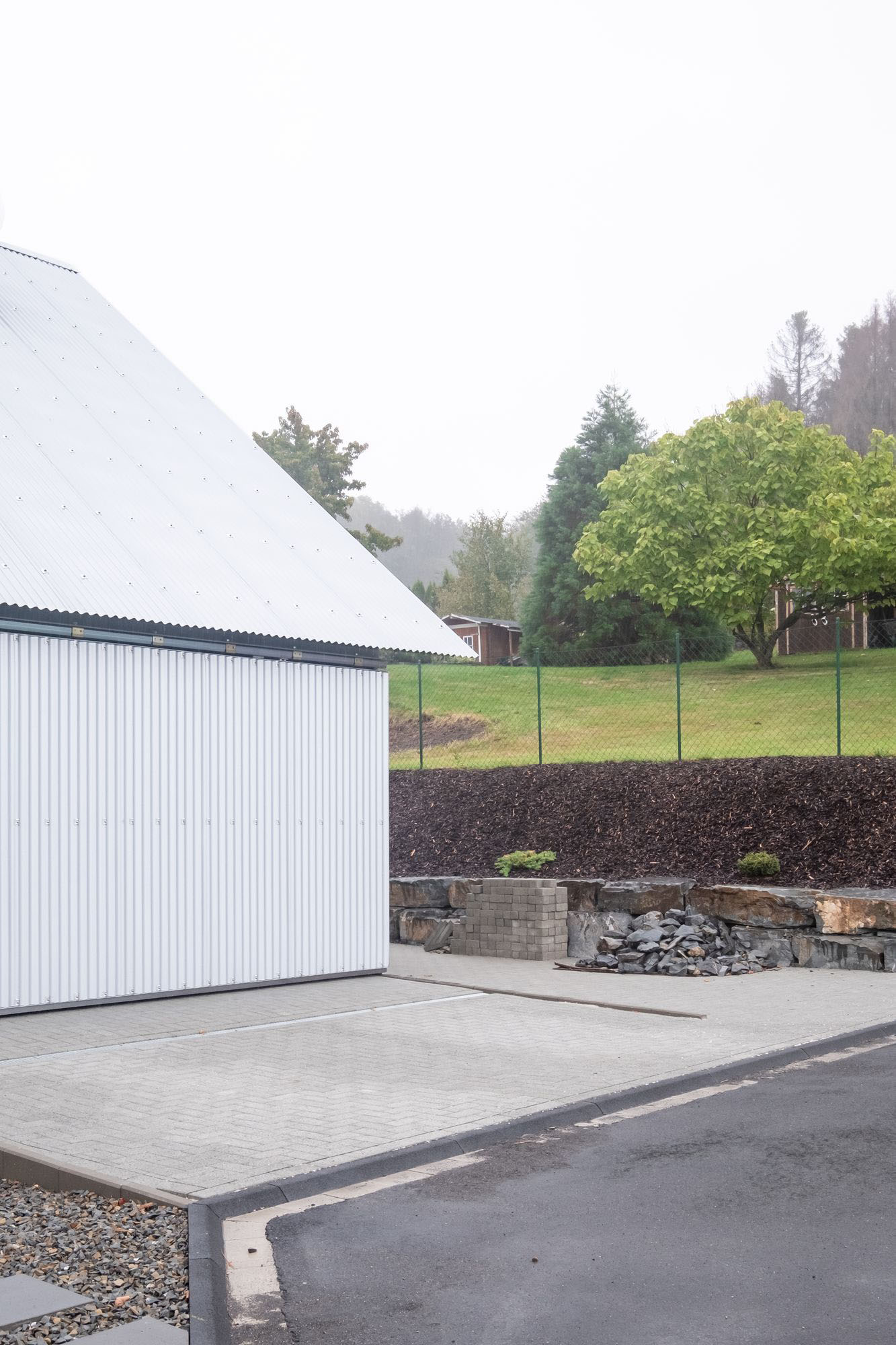 House D6 by Aretz Dürr Architektur — A low-cost agricultural building with a steeply pitched white metal roof dominates the composition.