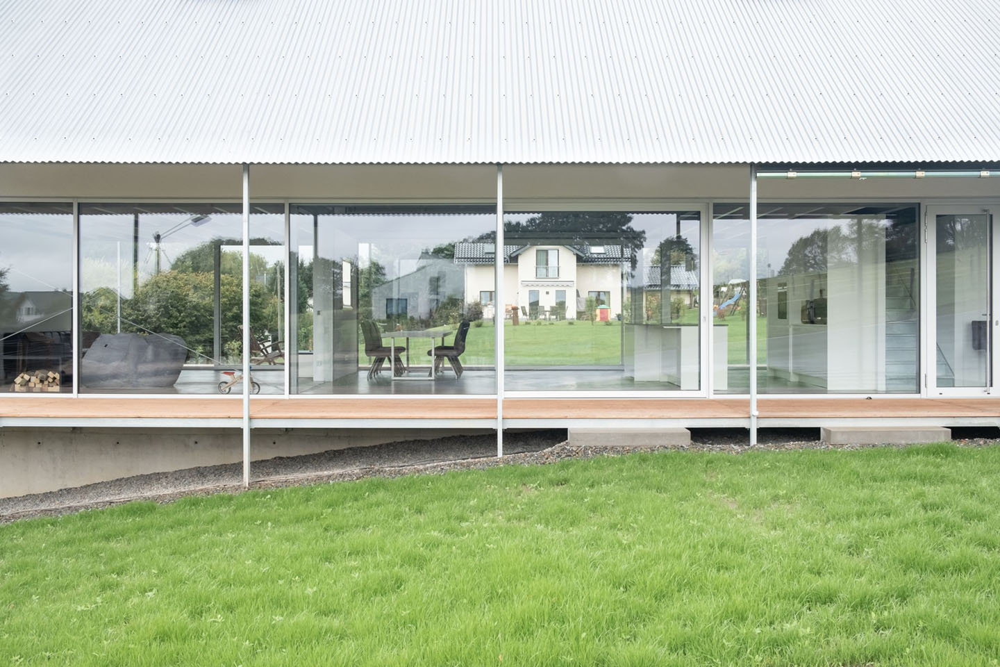 House D6 by Aretz Dürr Architektur — The southern facade presents an uninterrupted glazed threshold fronting the landscape, its continuous glass expanse subdivided by white steel mullions at...