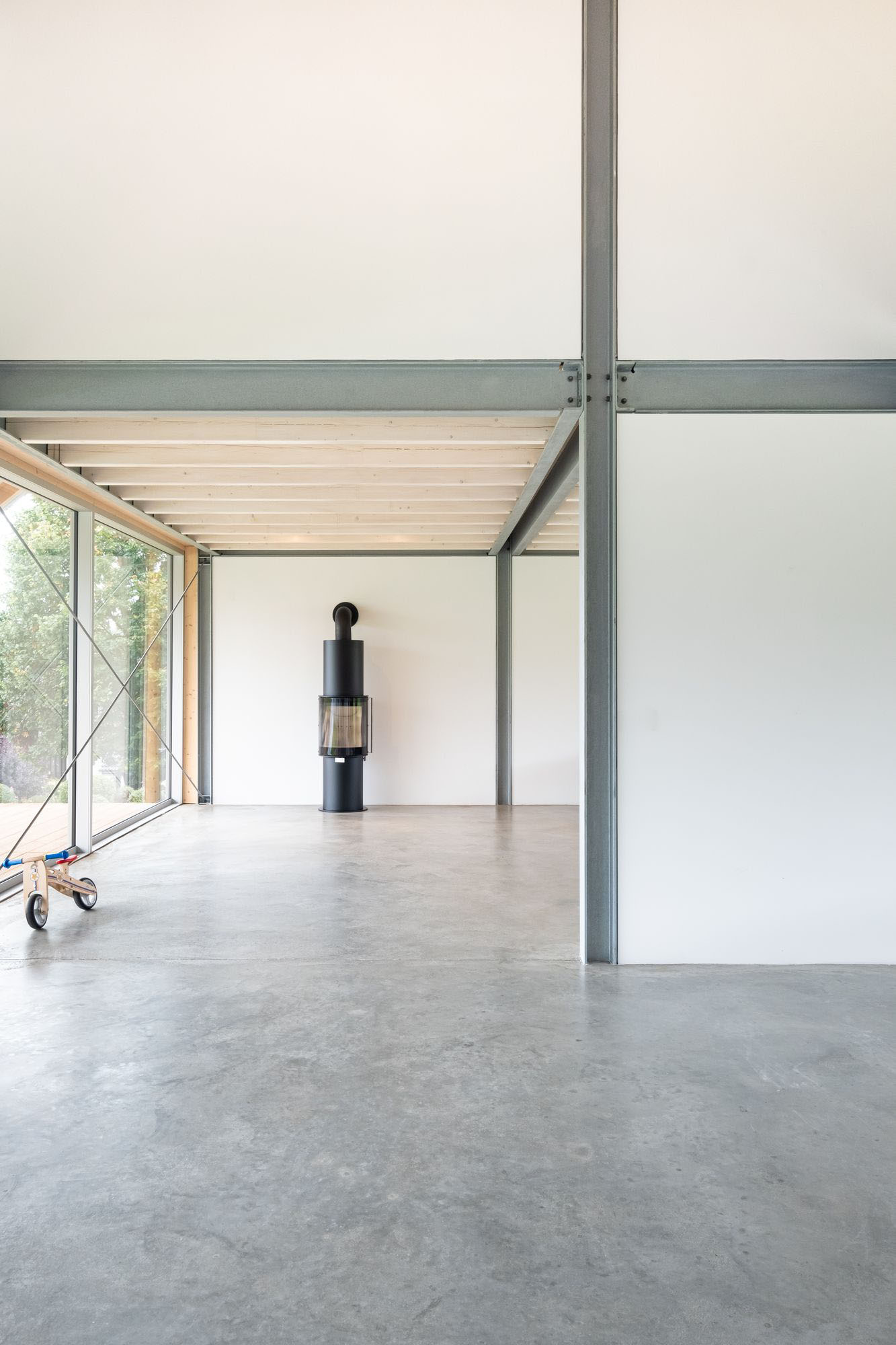House D6 by Aretz Dürr Architektur — A double-height interior volume defined by a central steel column rising through polished concrete flooring.
