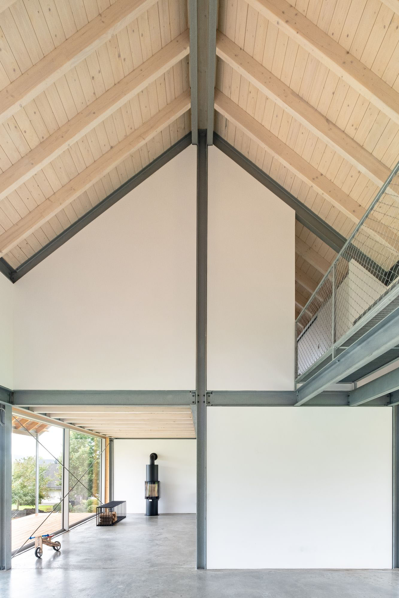 House D6 by Aretz Dürr Architektur — The double-height interior of House D6 demonstrates structural clarity through a central steel column that bisects the open-plan living space.