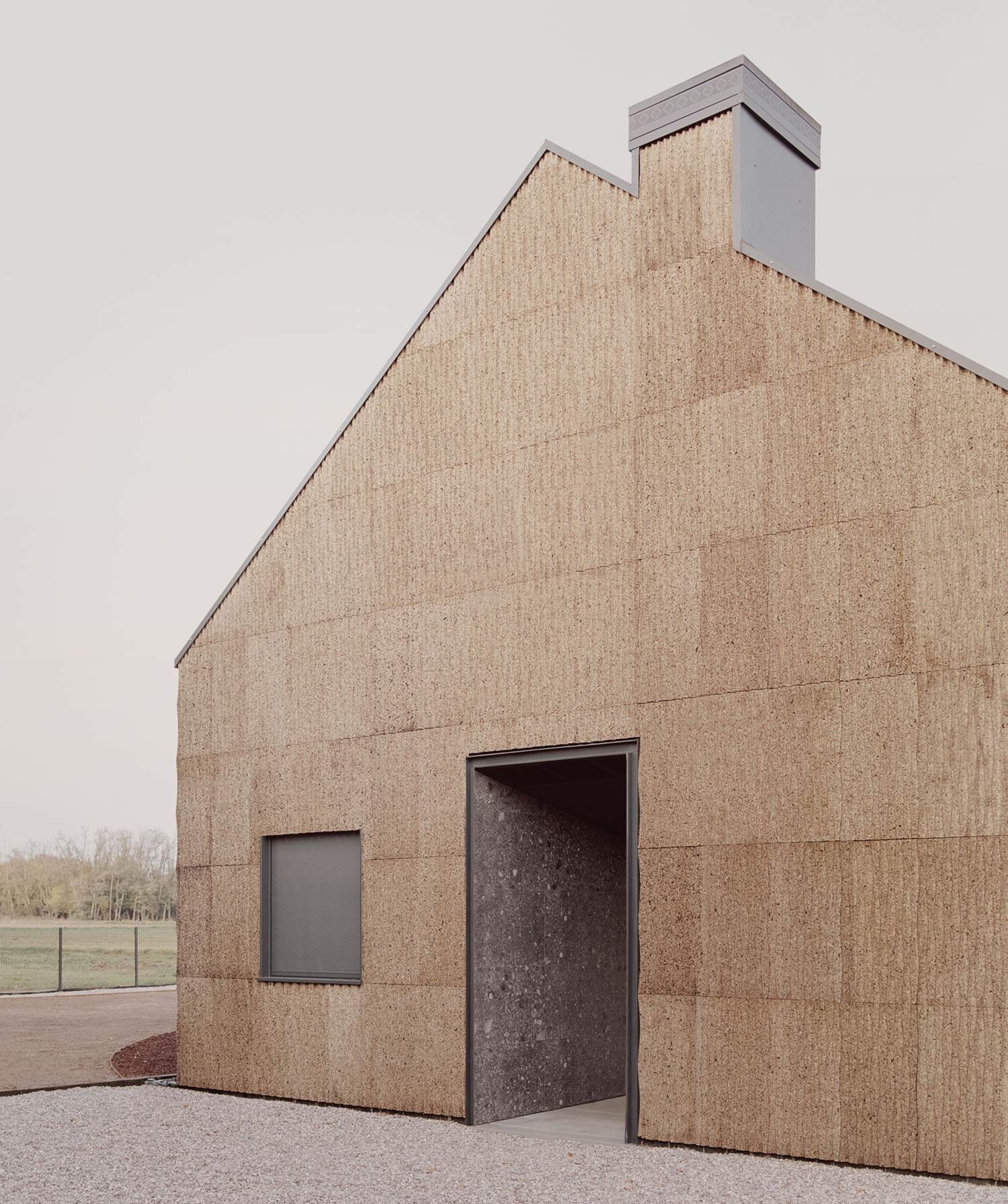 Casa Quattro by LCA Architetti — Casa Quattro presents a gabled volume clad entirely in cork, its surface articulated by visible horizontal mortar joints and a subtle 3D pantograph texture...