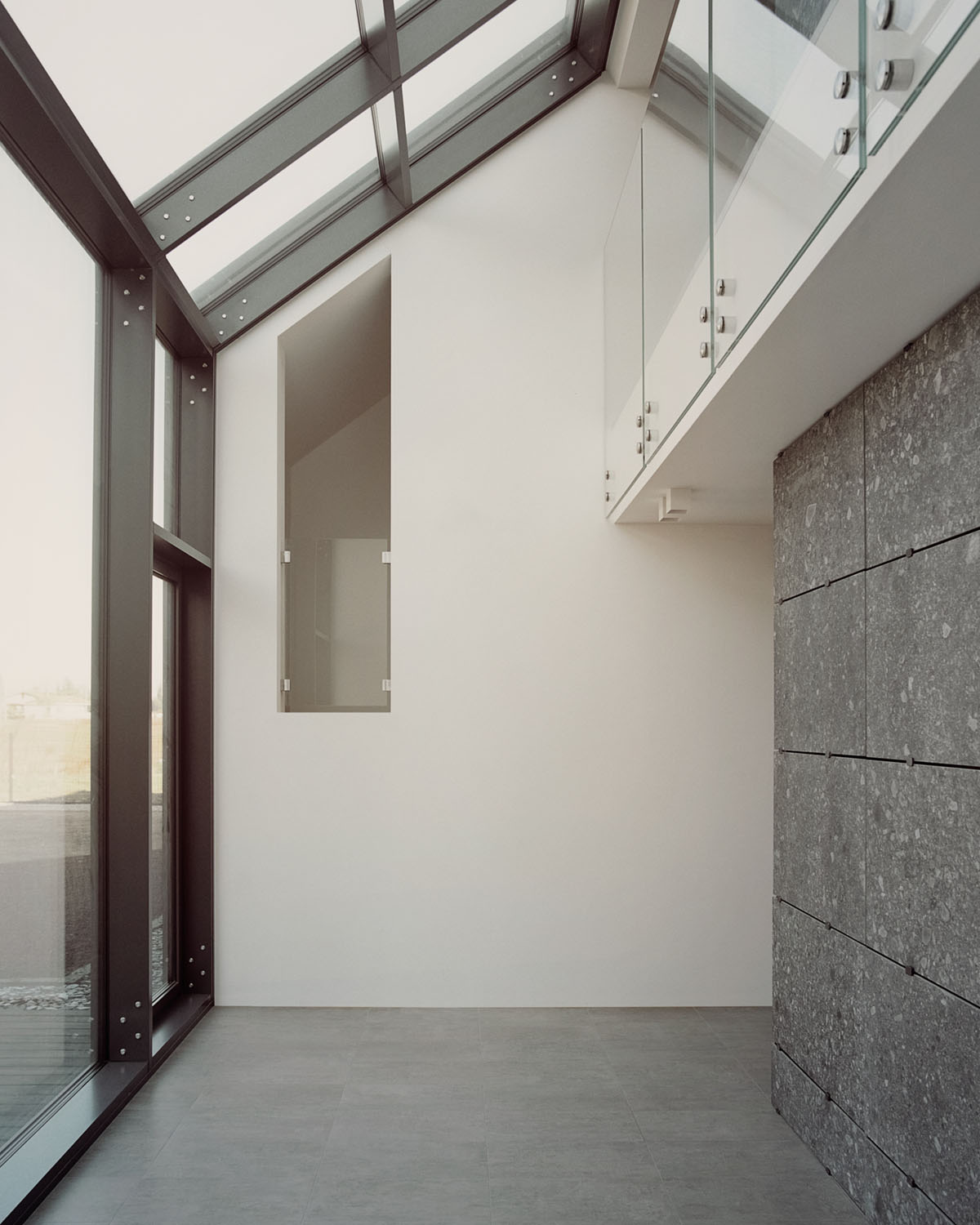 Casa Quattro by LCA Architetti — Interior passage framed by a dark-metal structural portal with visible fastener details.