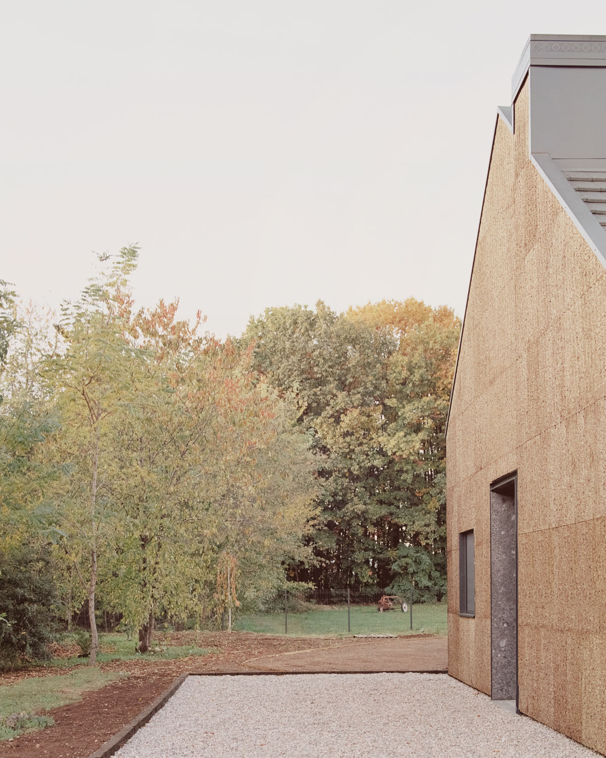 Casa Quattro by LCA Architetti — Casa Quattro's eastern facade presents a monolithic cork-clad volume adjacent to mature woodland.