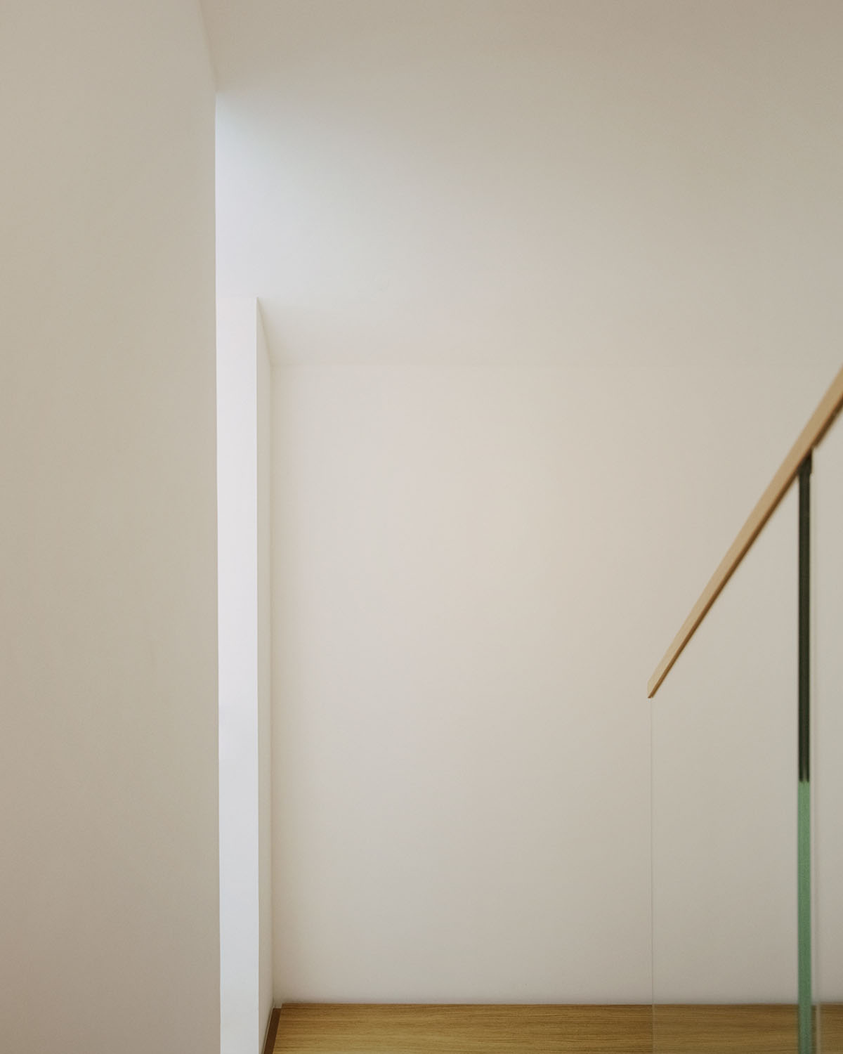 Casa Quattro by LCA Architetti — A stairwell corner in Casa Quattro captures the intersection of white rendered walls and wooden flooring.