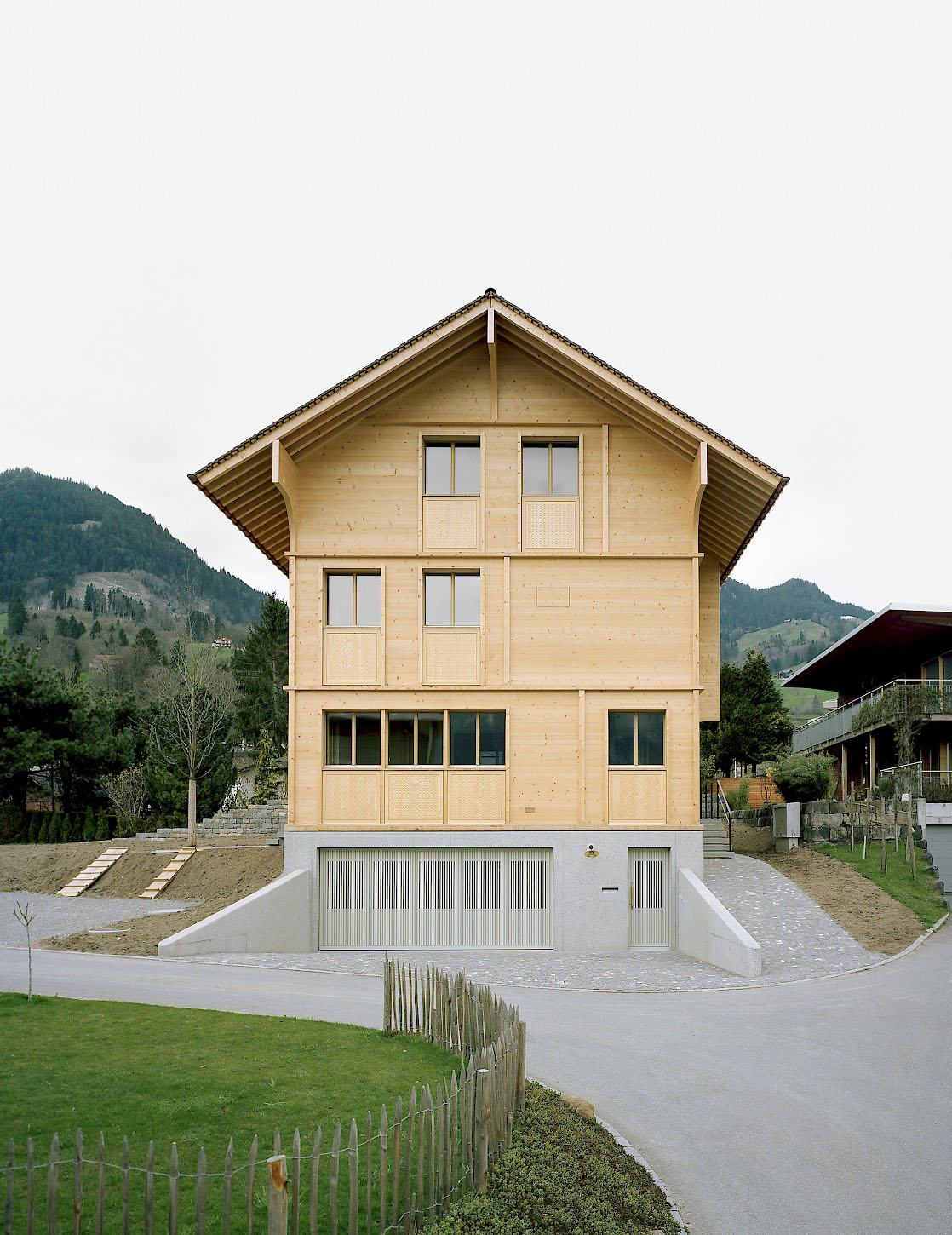 House K Alpnach by Seilerlinhart — House K Alpnach presents a timber-clad residential tower positioned on an elevated concrete plinth in the Swiss Alps.