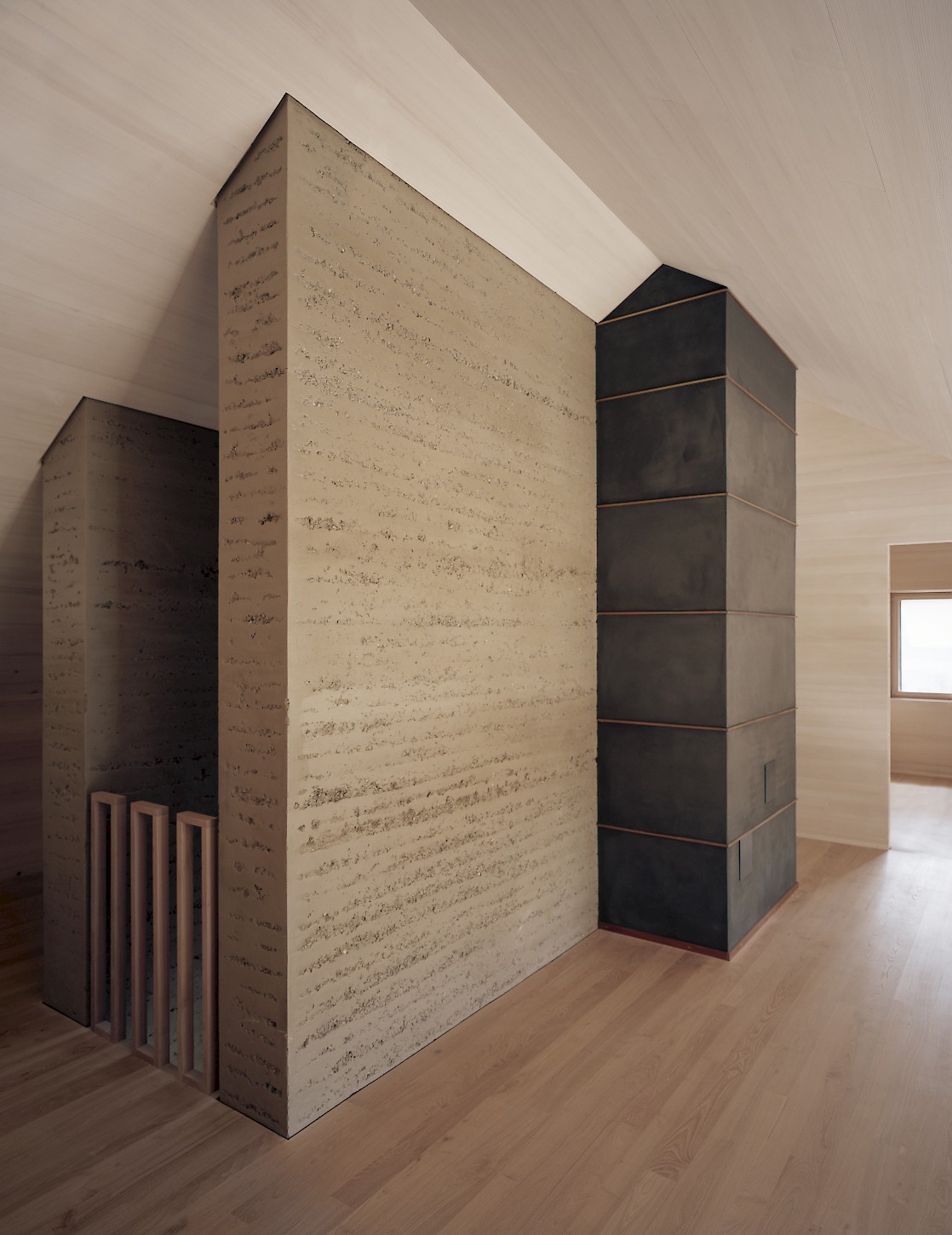House K Alpnach by Seilerlinhart — Interior view of a timber-clad volumetric form constructed from cork-textured boards with visible horizontal grain patterns.