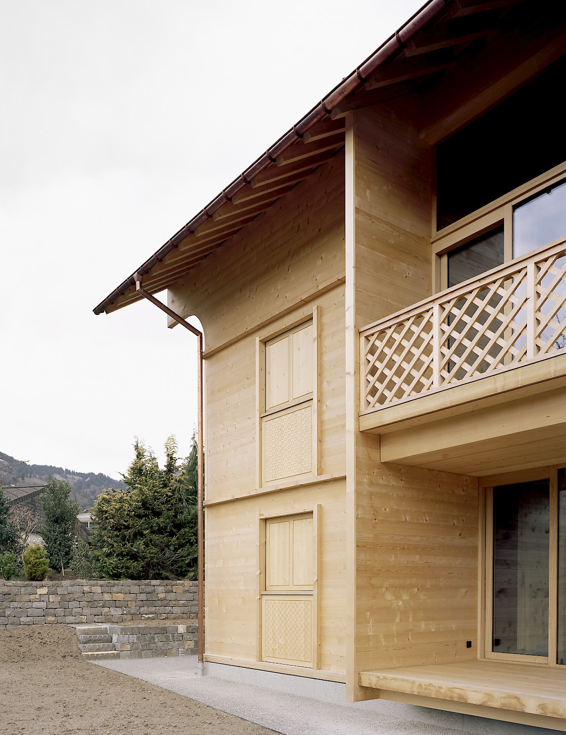 House K Alpnach by Seilerlinhart — House K Alpnach presents a three-story timber facade composed of light wood cladding with visible grain texture, punctuated by regularly spaced window...