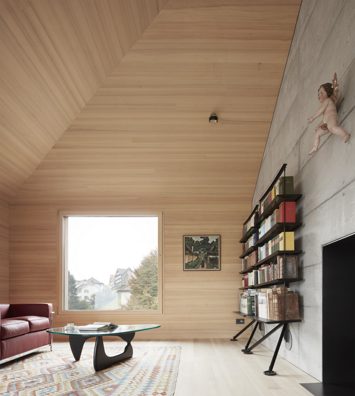 House at the Schopfacker by Bernardo Bader Architects — An open-plan living space defined by continuous horizontal timber slat cladding on walls and ceiling, creating a unified wooden envelope.