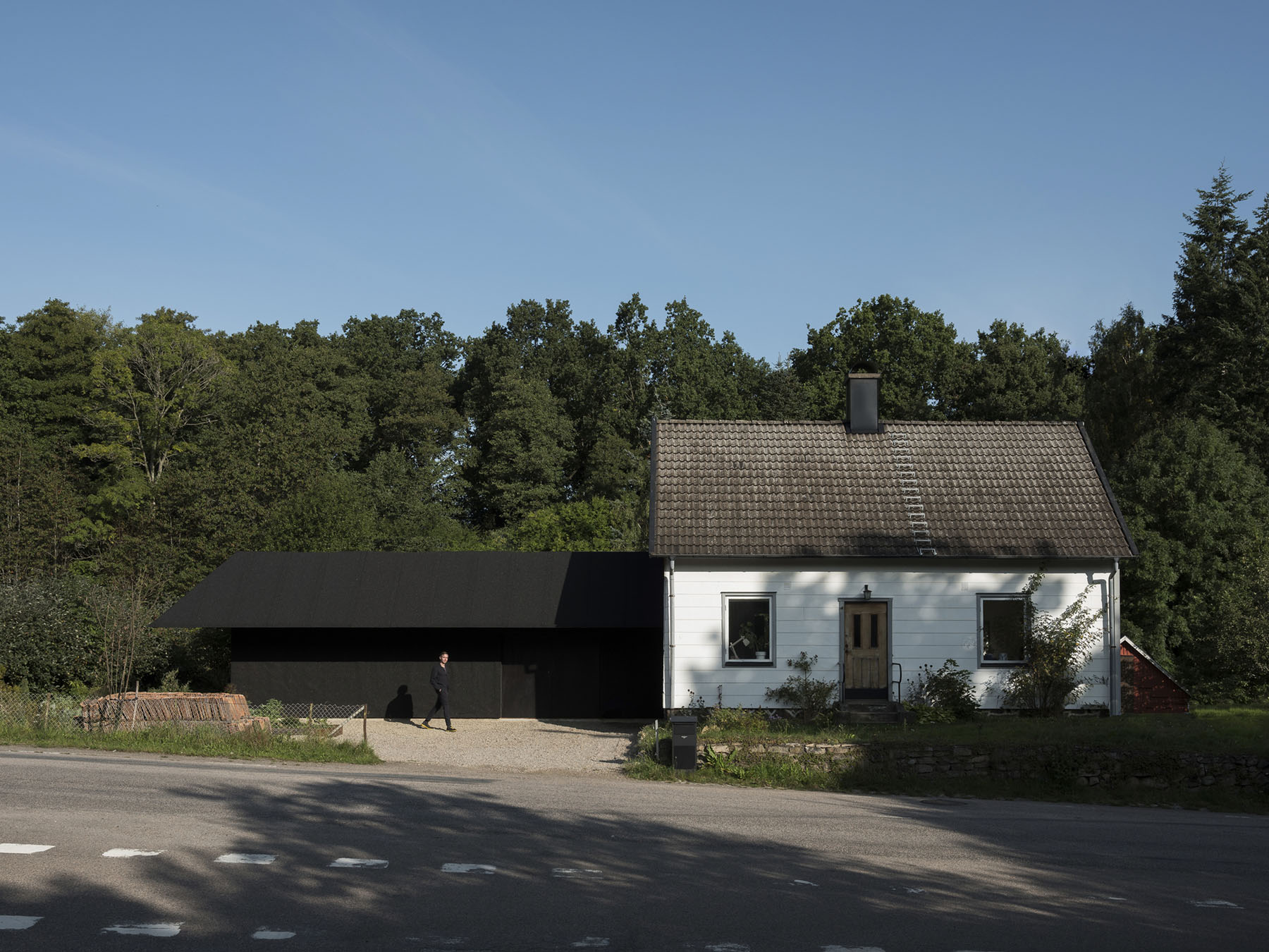 House for Two Artists by Förstberg Ling — The extension building presents a studied contrast between its modernist black timber-clad volume on the left and the restored white-painted original villa...