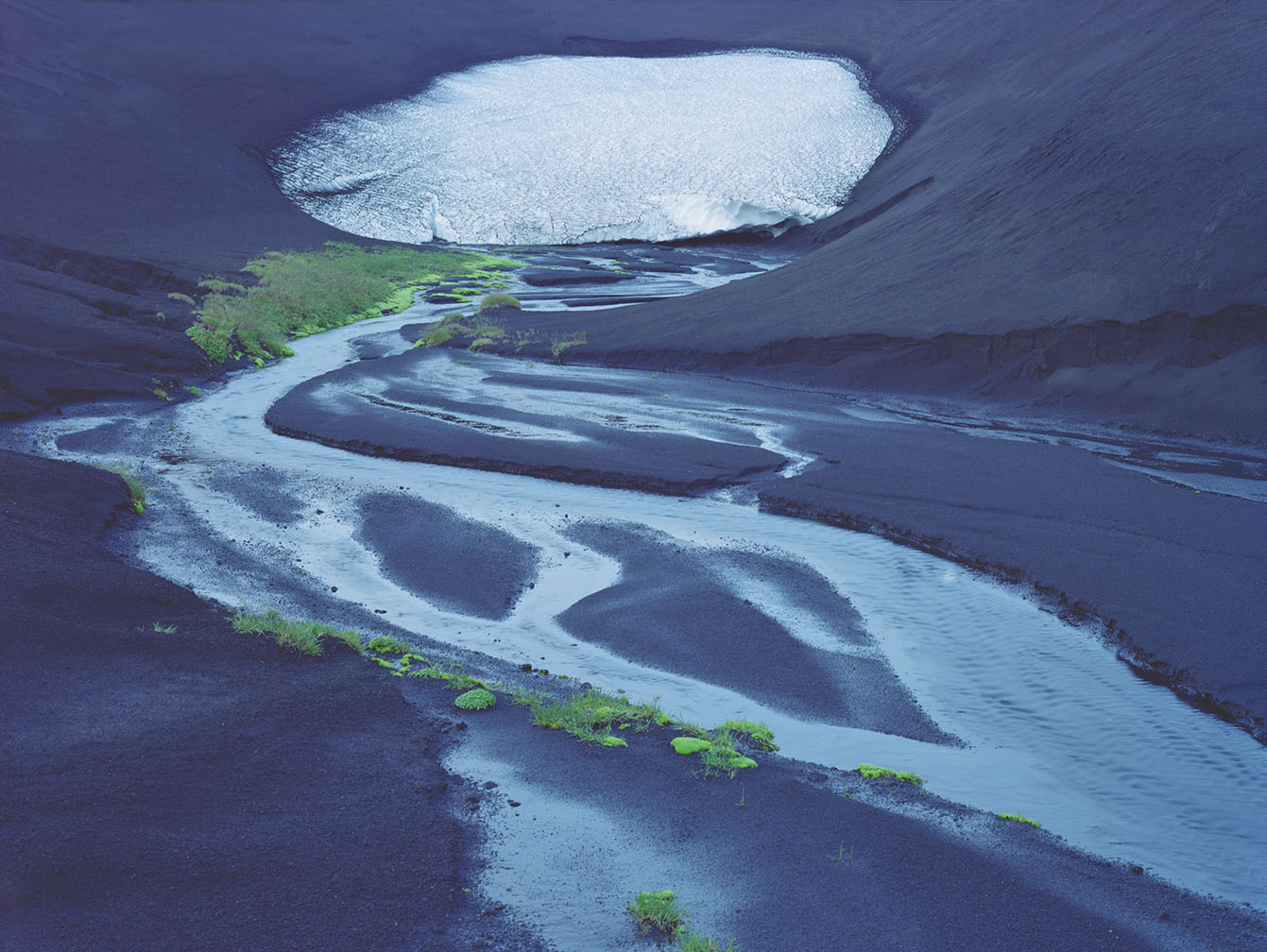 Breathtaking Landscapes by Luca Tombolini — Aerial view of an Icelandic valley floor revealing a braided glacial river system cutting through dark volcanic basalt.