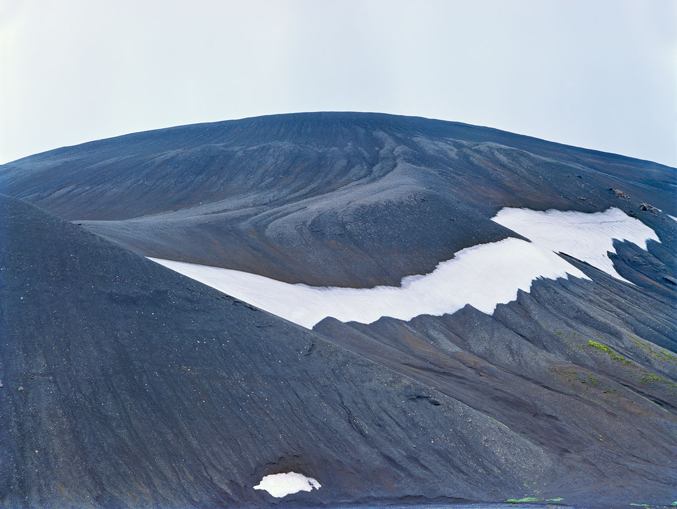 Breathtaking Landscapes by Luca Tombolini — A volcanic crater reveals its geological stratification through exposed rhyolite ridges marked by sharp angular striations running diagonally across the...