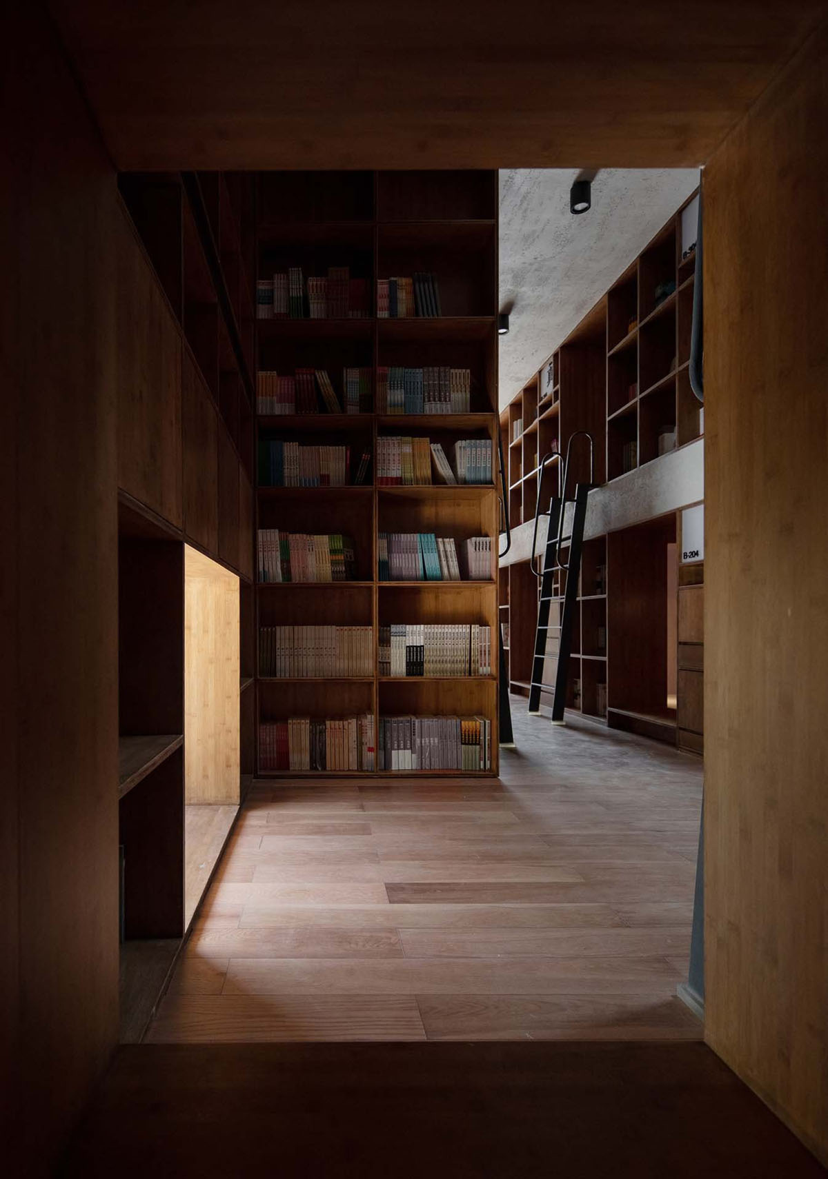 Capsule Hotel and Bookstore in Village Qinglongwu by Atelier tao+c — Interior passage of the capsule hotel and bookstore renovation, framed through a narrow wood-lined corridor.
