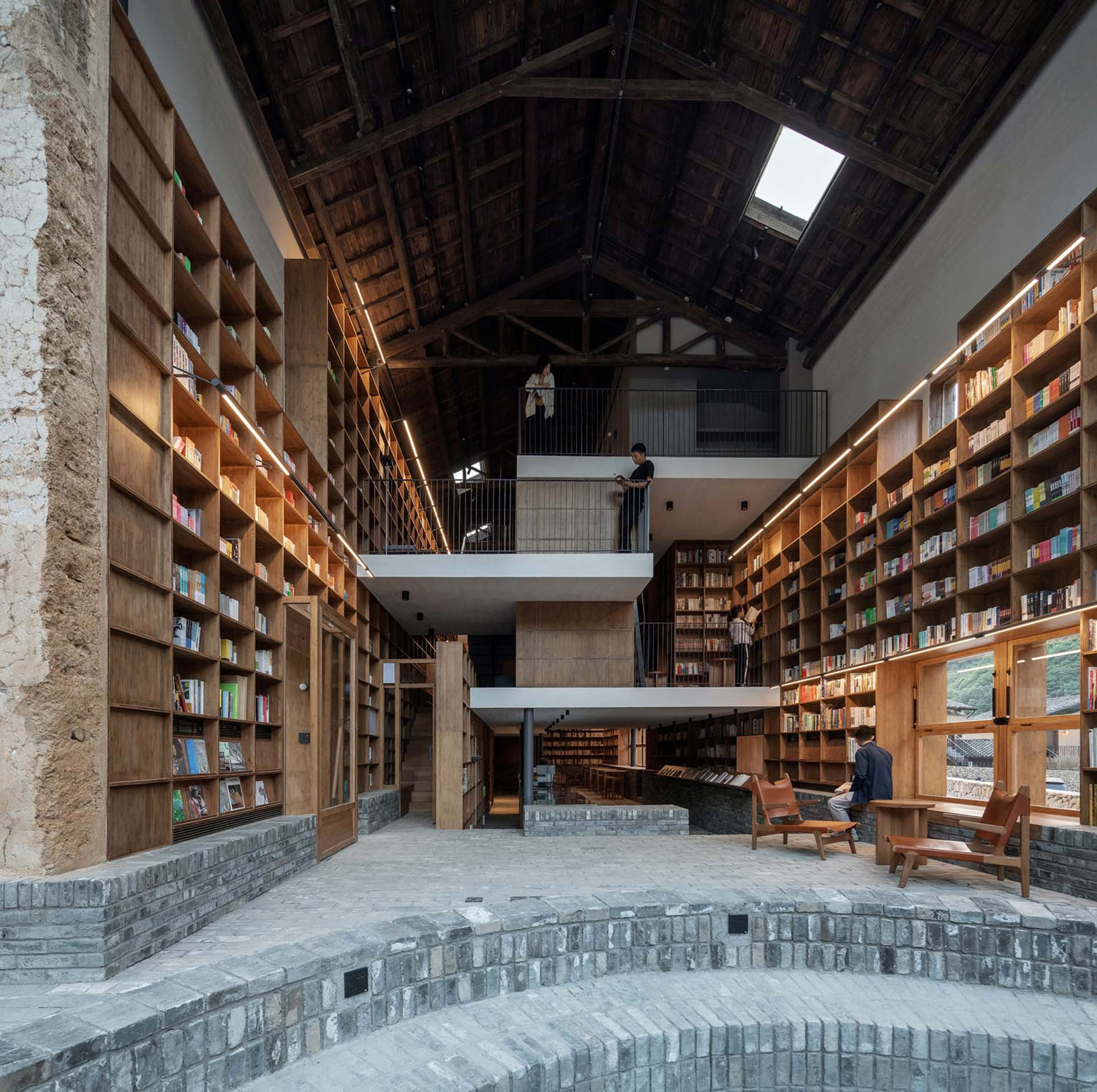 Capsule Hotel and Bookstore in Village Qinglongwu by Atelier tao+c — Interior view of a multi-story bookstore and capsule hotel within a converted vernacular structure.
