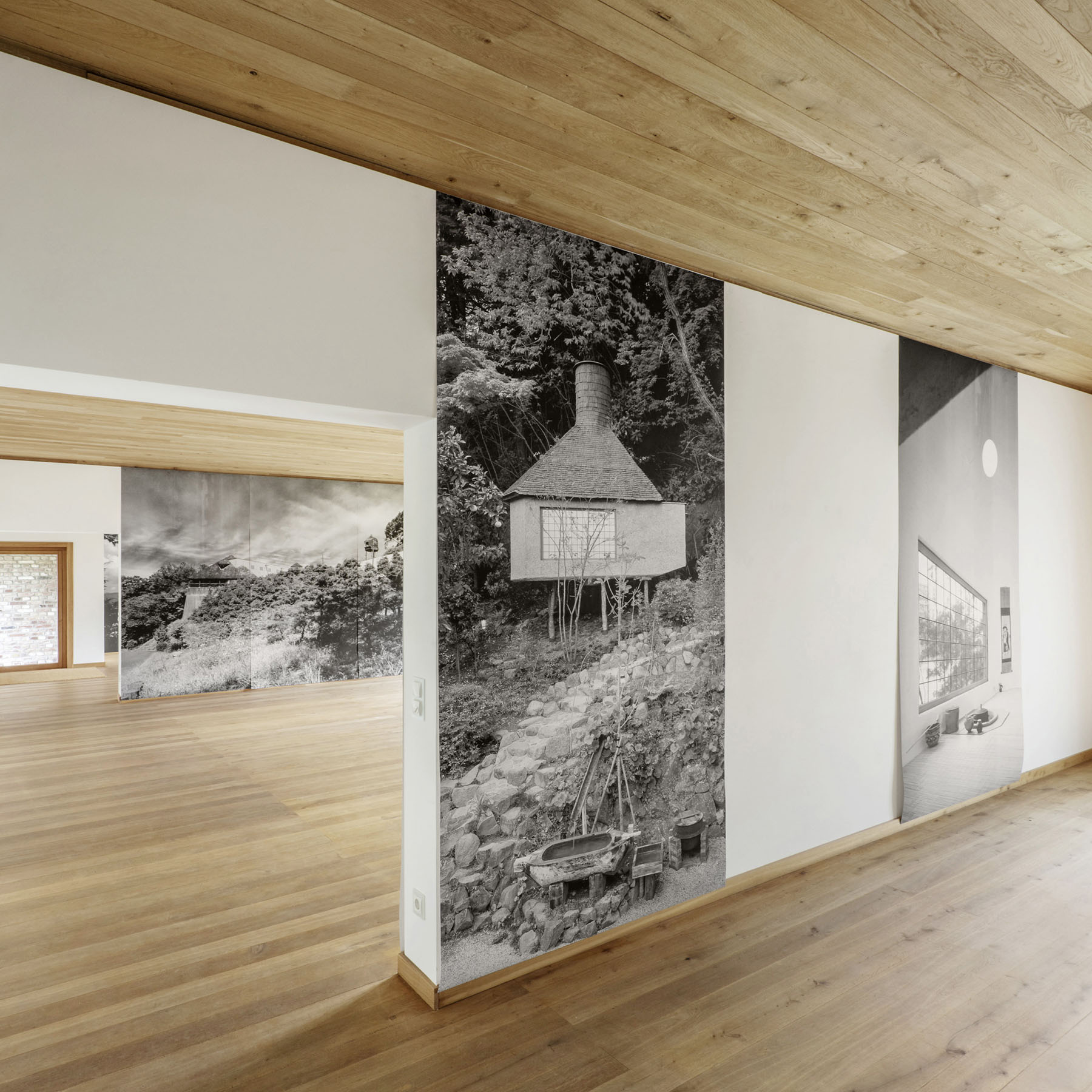 Ein Stein Tea House and Other Architectures by Terunobu Fujimori — Interior exhibition view of the Ein Stein Tea House displaying large-format black-and-white photographs mounted on white walls.