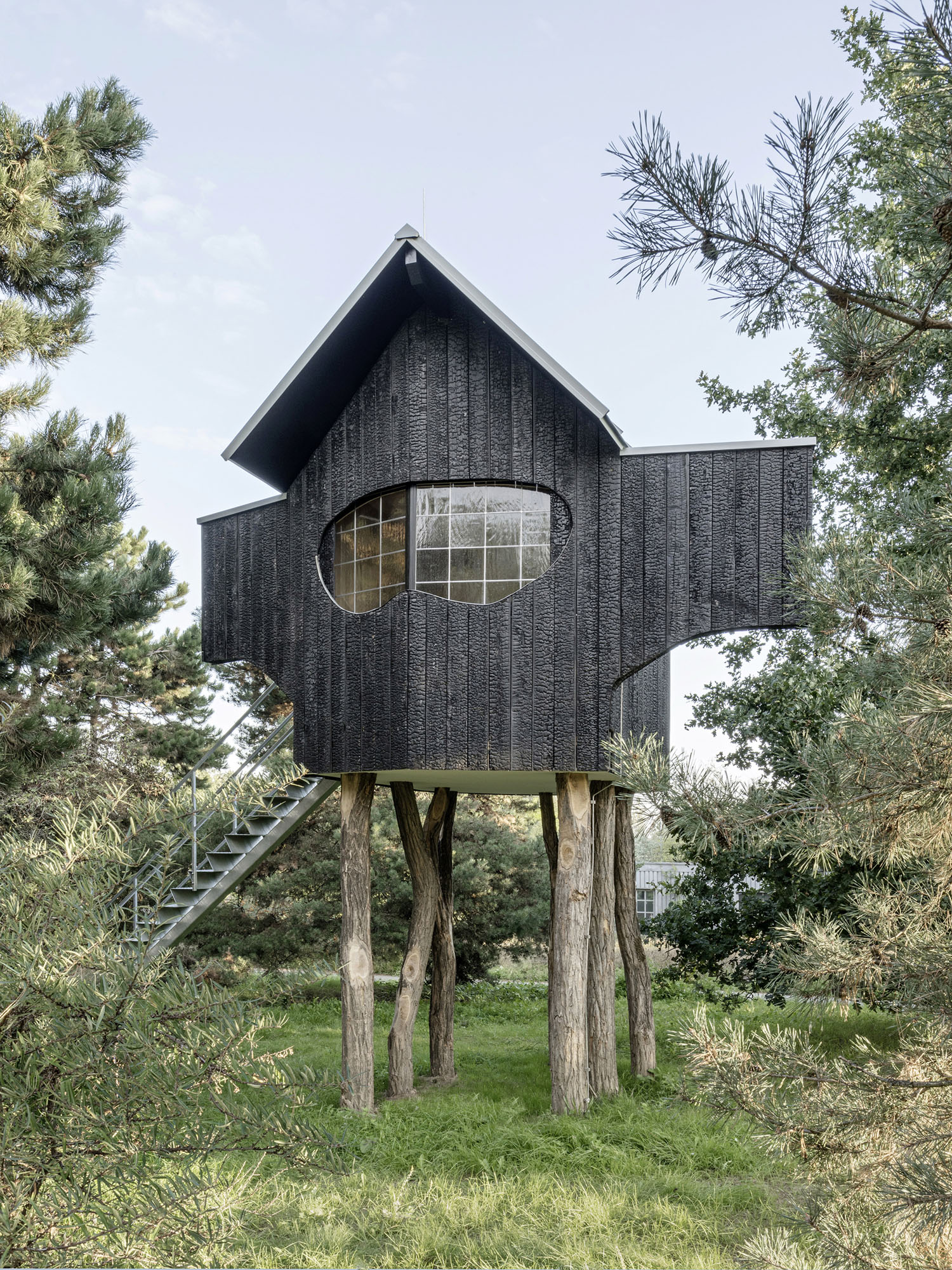 Ein Stein Tea House and Other Architectures by Terunobu Fujimori — Terunobu Fujimori's Ein Stein Tea House rises on weathered robinia timber posts within a densely planted garden setting.