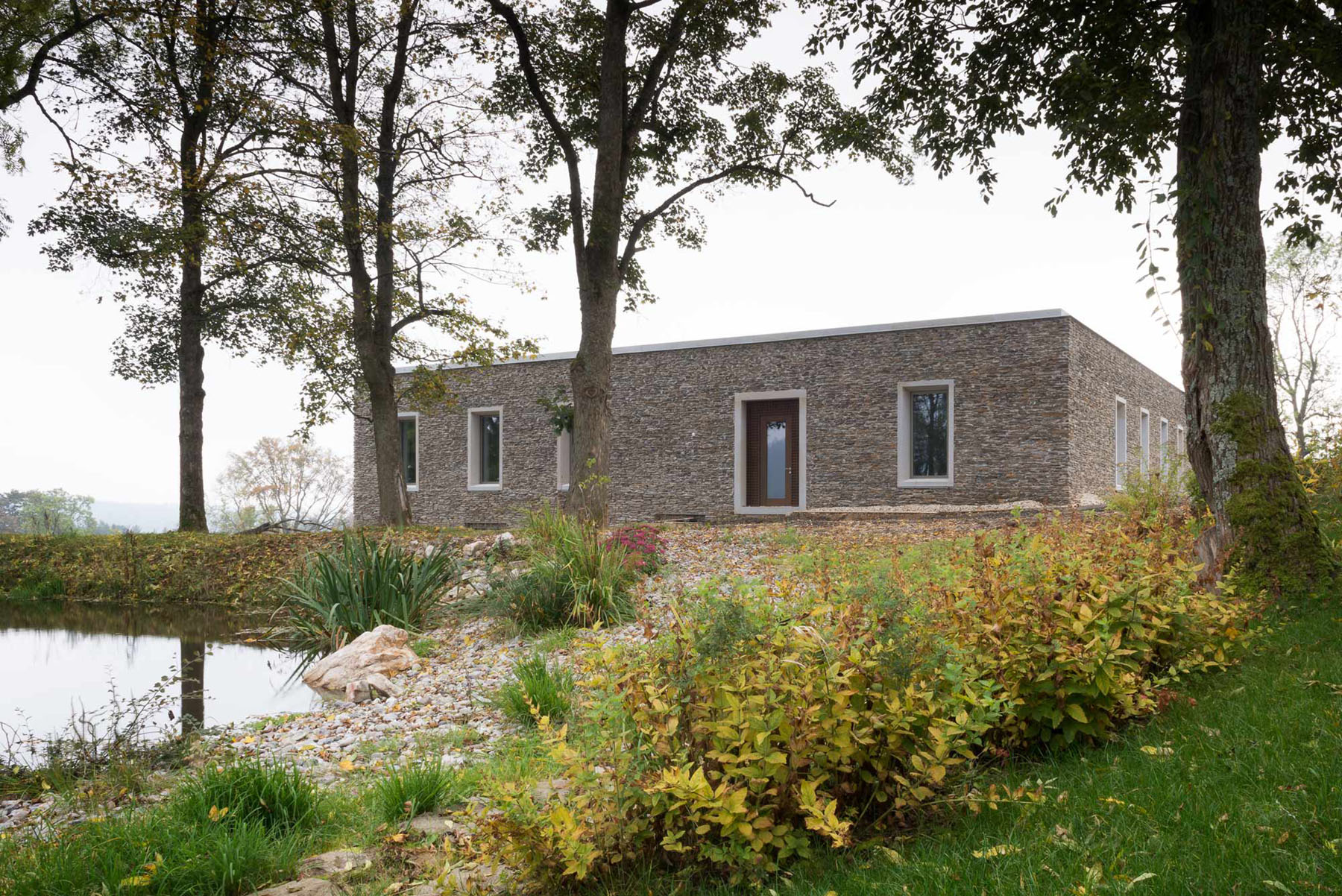 Nový Dvůr Industry by John Pawson — The rendered brick facade presents a restrained composition of flush rectangular windows set in regular rhythm across the building's length.