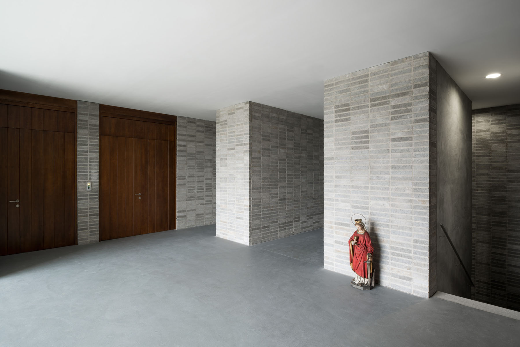 Nový Dvůr Industry by John Pawson — Interior passage of the Nový Dvůr monastery workshops showing rendered masonry walls arranged in a rhythmic grid pattern of horizontal bands.