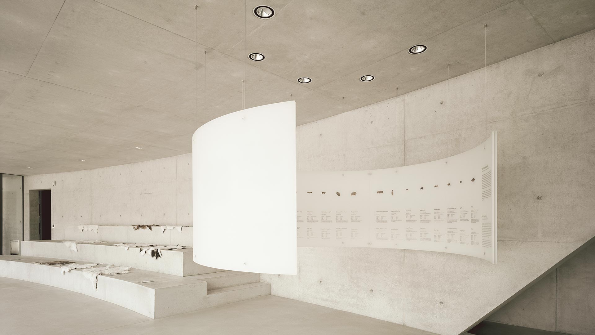 Information Center Archäopark Vogelherd by Ritter Jockisch Architects — Interior view of the Information Center's exhibition hall, revealing the architectural strategy of layered transparency and concealment.