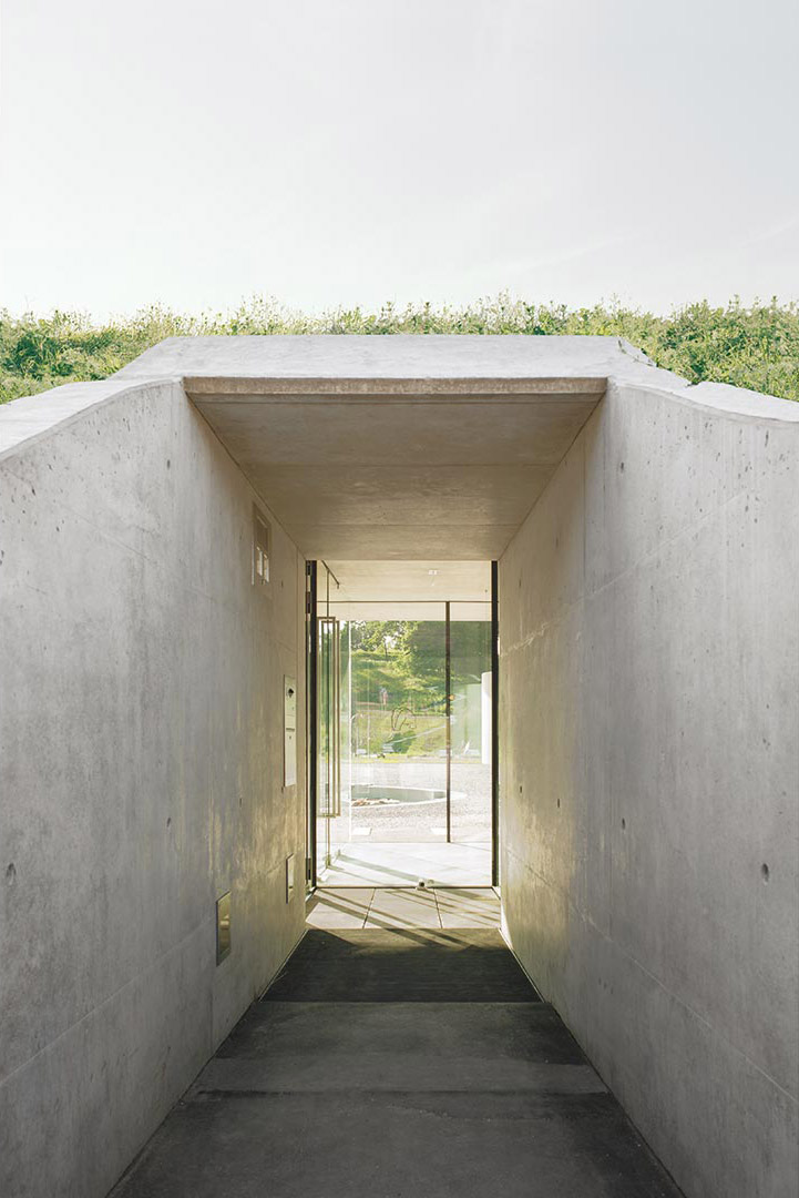 Information Center Archäopark Vogelherd by Ritter Jockisch Architects — A concrete passage carved through an earthen berm serves as the primary approach to the Information Center.