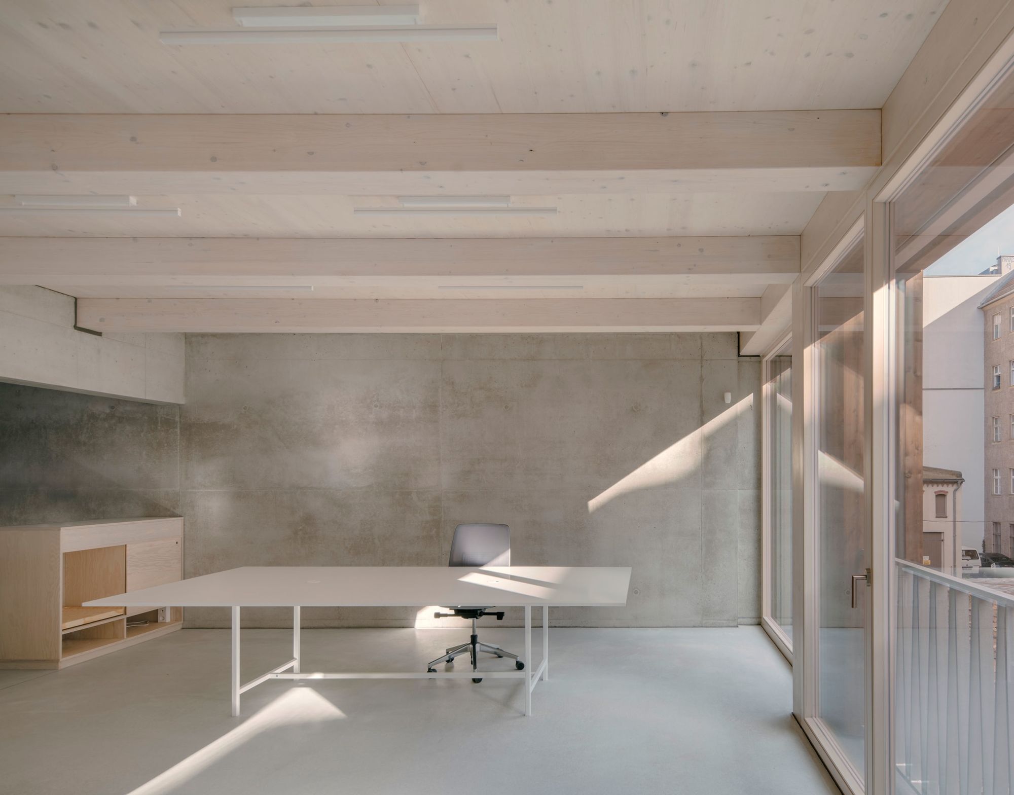 REMISE by Jan Wiese Architects — A renovated office interior within the REMISE complex features a minimalist workspace defined by material contrast and natural light.