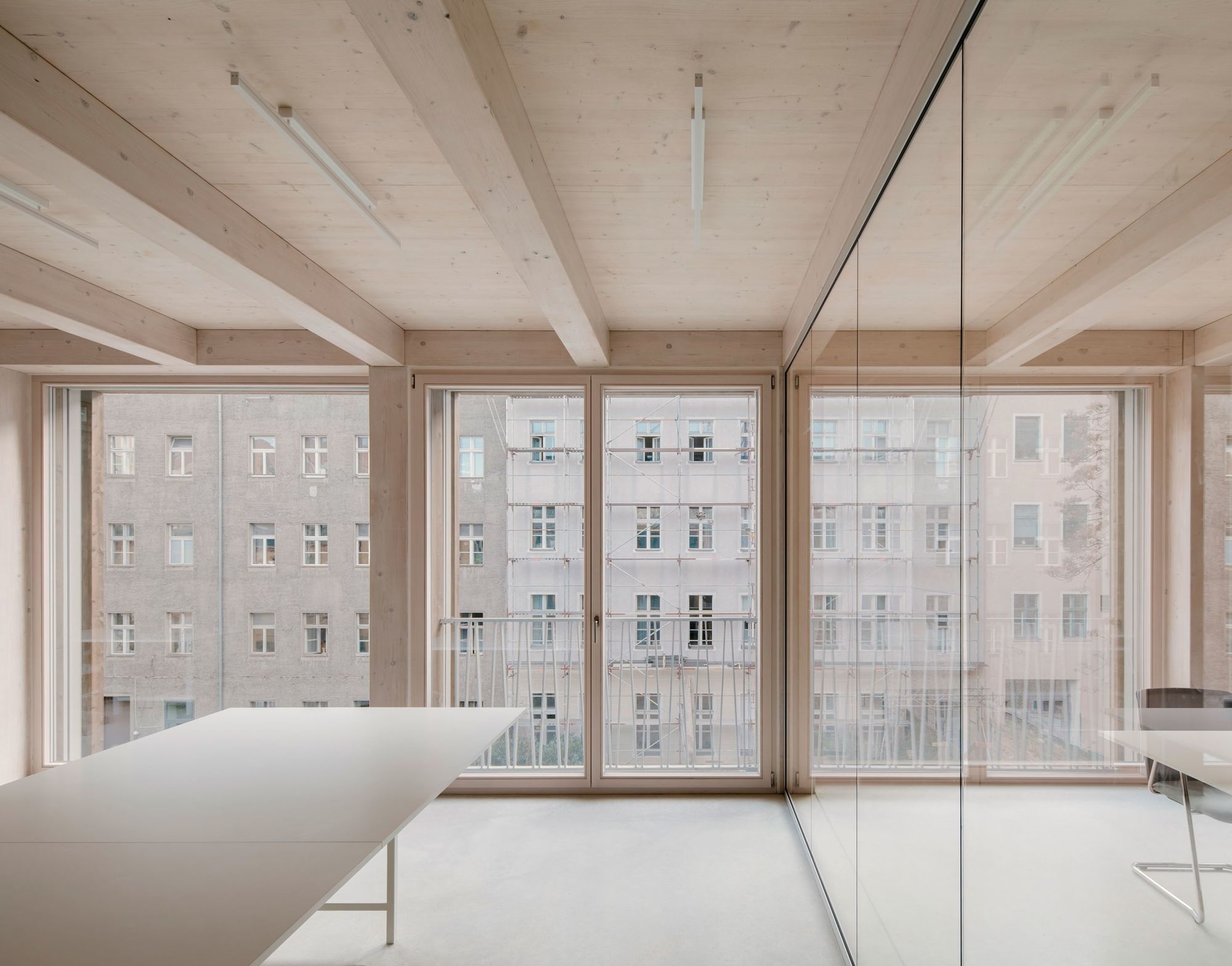 REMISE by Jan Wiese Architects — A glazed interior workspace overlooks a Berlin courtyard of preserved brick buildings.