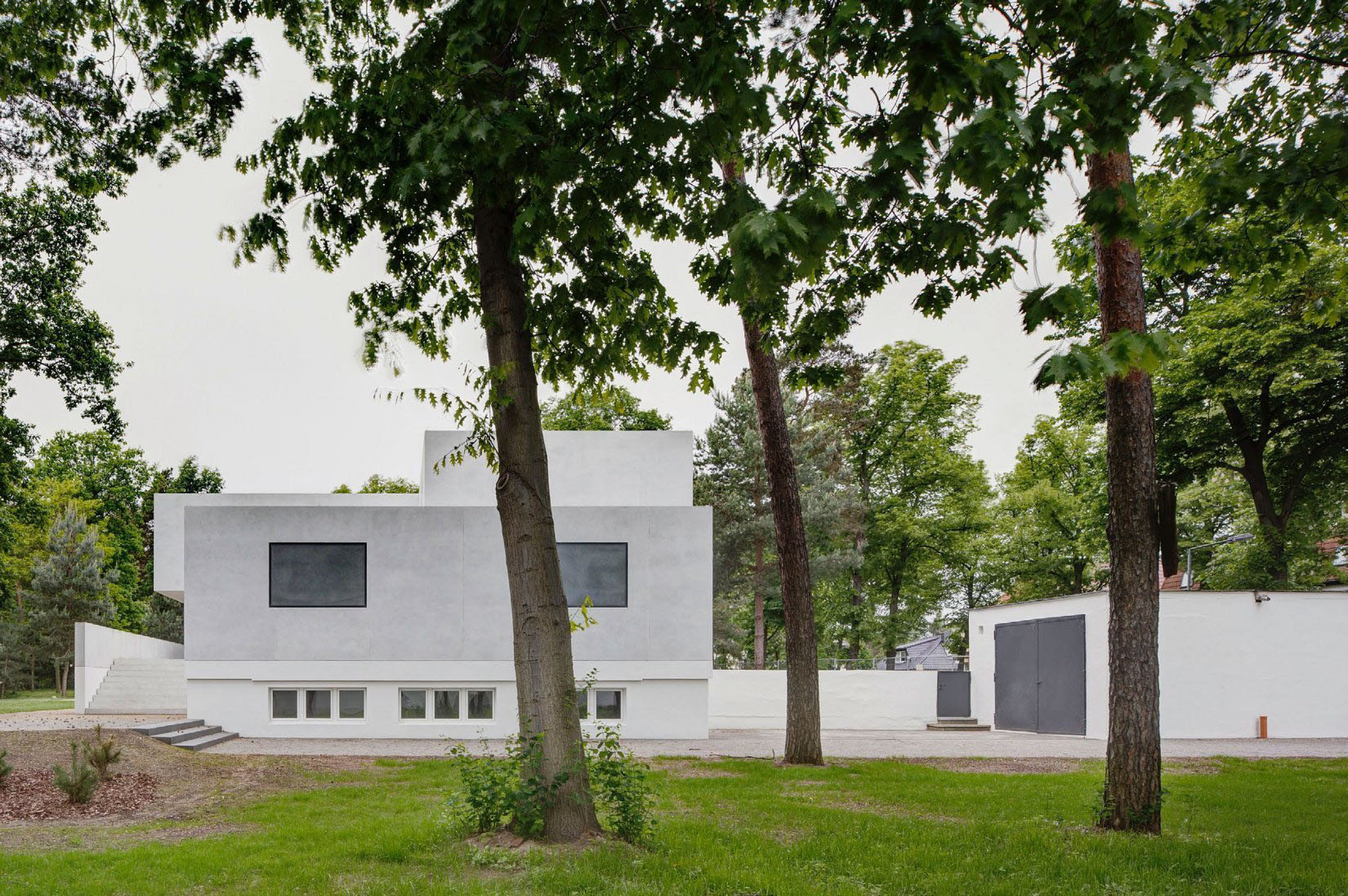 Neue Meisterhäuser Bauhaus Dessau by Bruno Fioretti Marquez — A monolithic concrete structure with flush-set rectangular windows anchors a densely wooded site in Dessau.