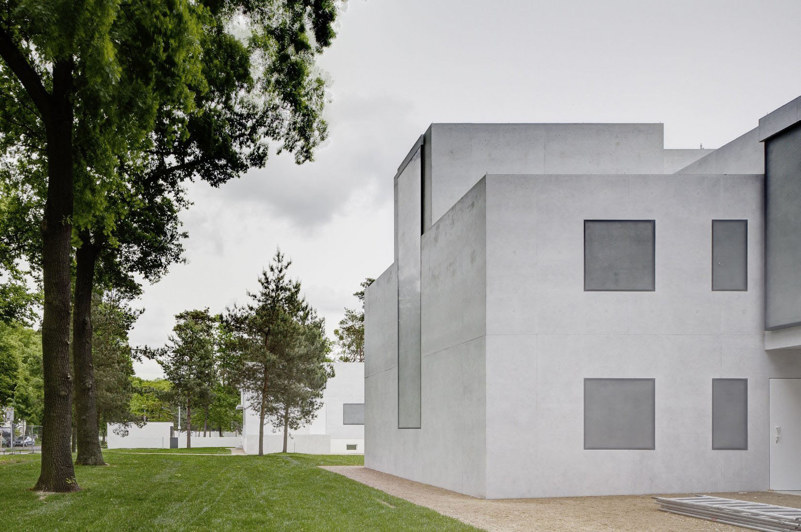 Neue Meisterhäuser Bauhaus Dessau by Bruno Fioretti Marquez — The reconstructed Meisterhäuser presents a monolithic concrete facade with flush-set recessed square windows arranged in a regular grid, their deep...
