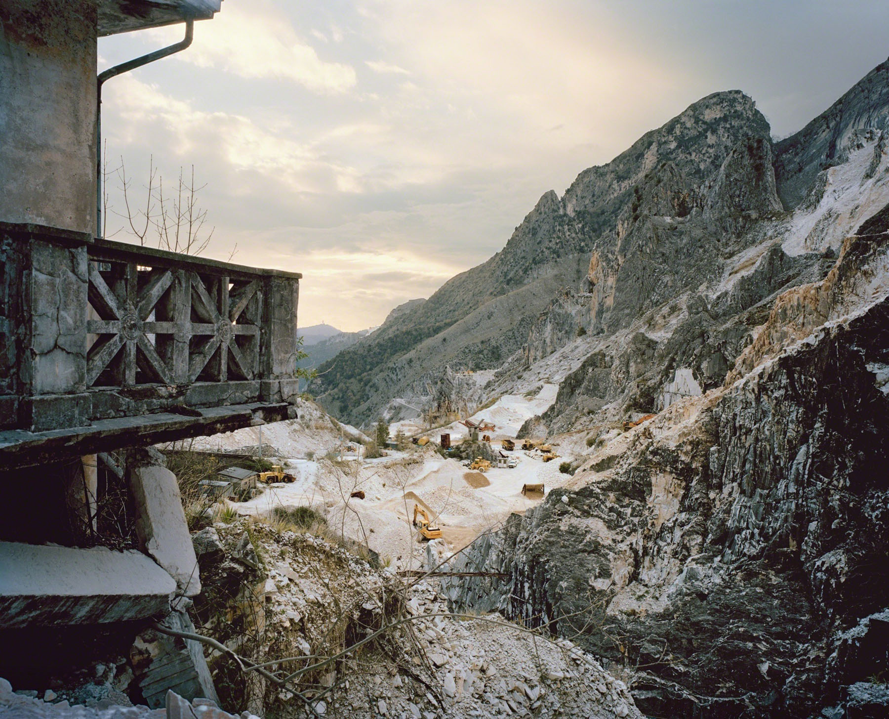 Aftermath by Jörn Vanhöfen — A marble quarry operation sprawls across a mountain valley floor, captured from an elevated vantage point adjacent to industrial structures.