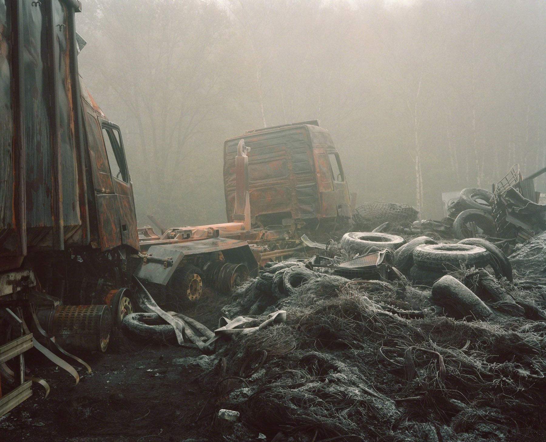 Aftermath by Jörn Vanhöfen — Heavy machinery and industrial debris scattered across a mist-shrouded landscape.