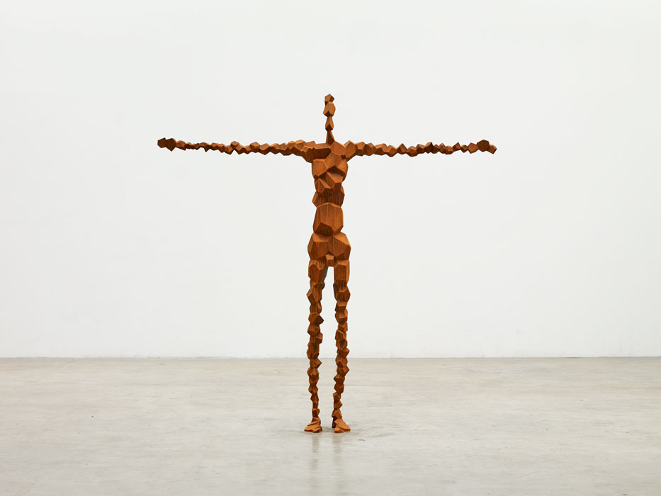 Sculptures by Antony Gormley — A life-scale wooden figure constructed from stacked rectangular timber blocks in varying sizes, assembled to approximate human anatomical proportions.