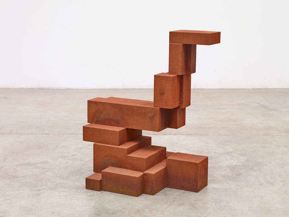 Sculptures by Antony Gormley — A timber sculpture assembled from stacked rectangular blocks of varying dimensions in warm terracotta and rust tones.