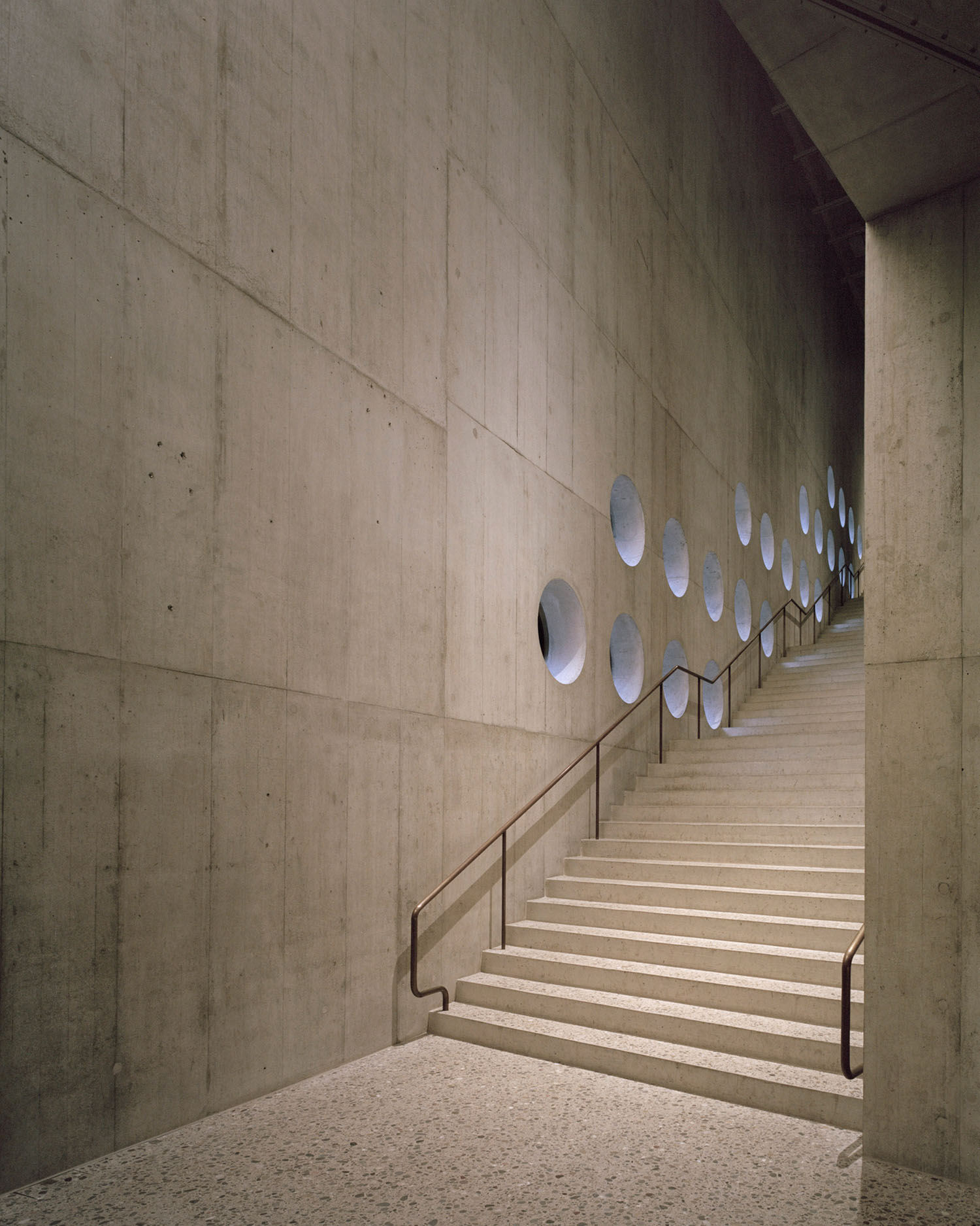 Swiss National Museum by Christ & Gantenbein photographed by Rory Gardiner — A staircase ascends through a monolithic concrete passage, its board-formed surfaces creating a rhythmic linear composition.