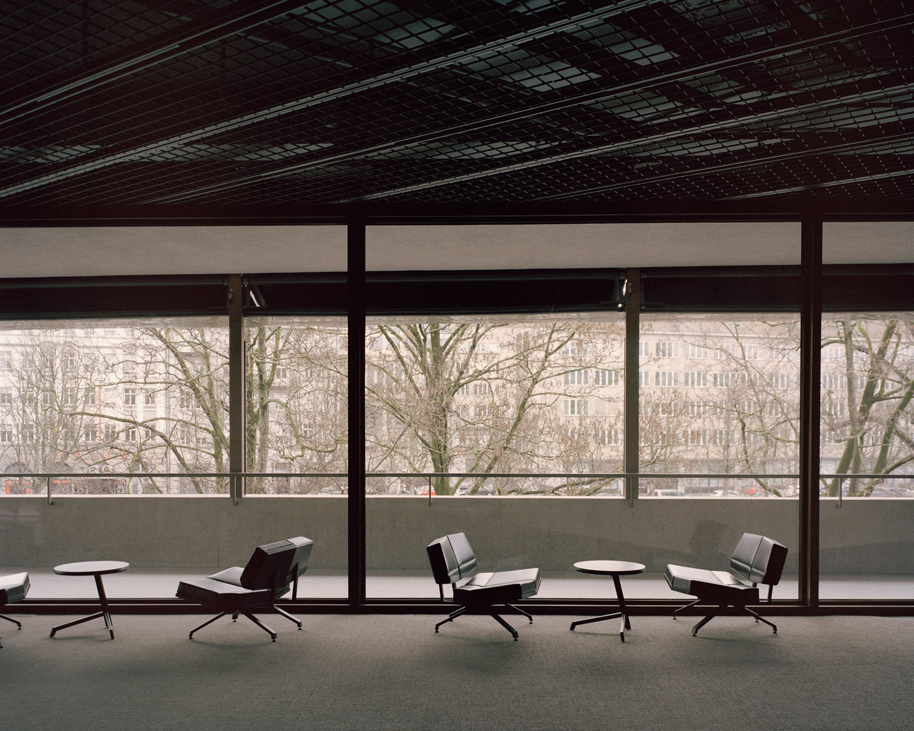 Swiss National Museum by Christ & Gantenbein photographed by Rory Gardiner — A glazed corridor overlooking Zurich's historic cityscape frames three modernist lounge chairs against expansive windows.
