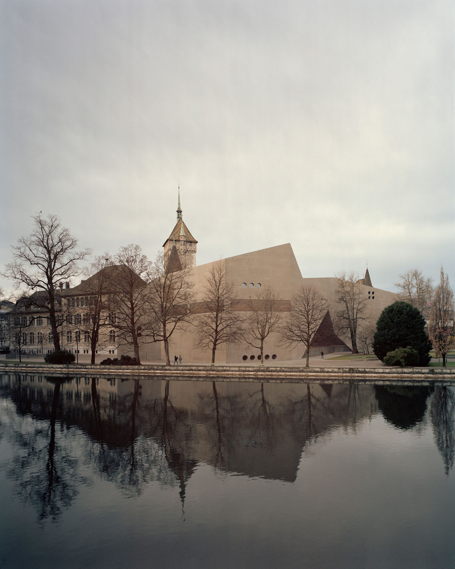 Swiss National Museum by Christ & Gantenbein photographed by Rory Gardiner — The Swiss National Museum's new wing by Christ & Gantenbein is photographed from across the adjacent water body, creating a mirror reflection of the...