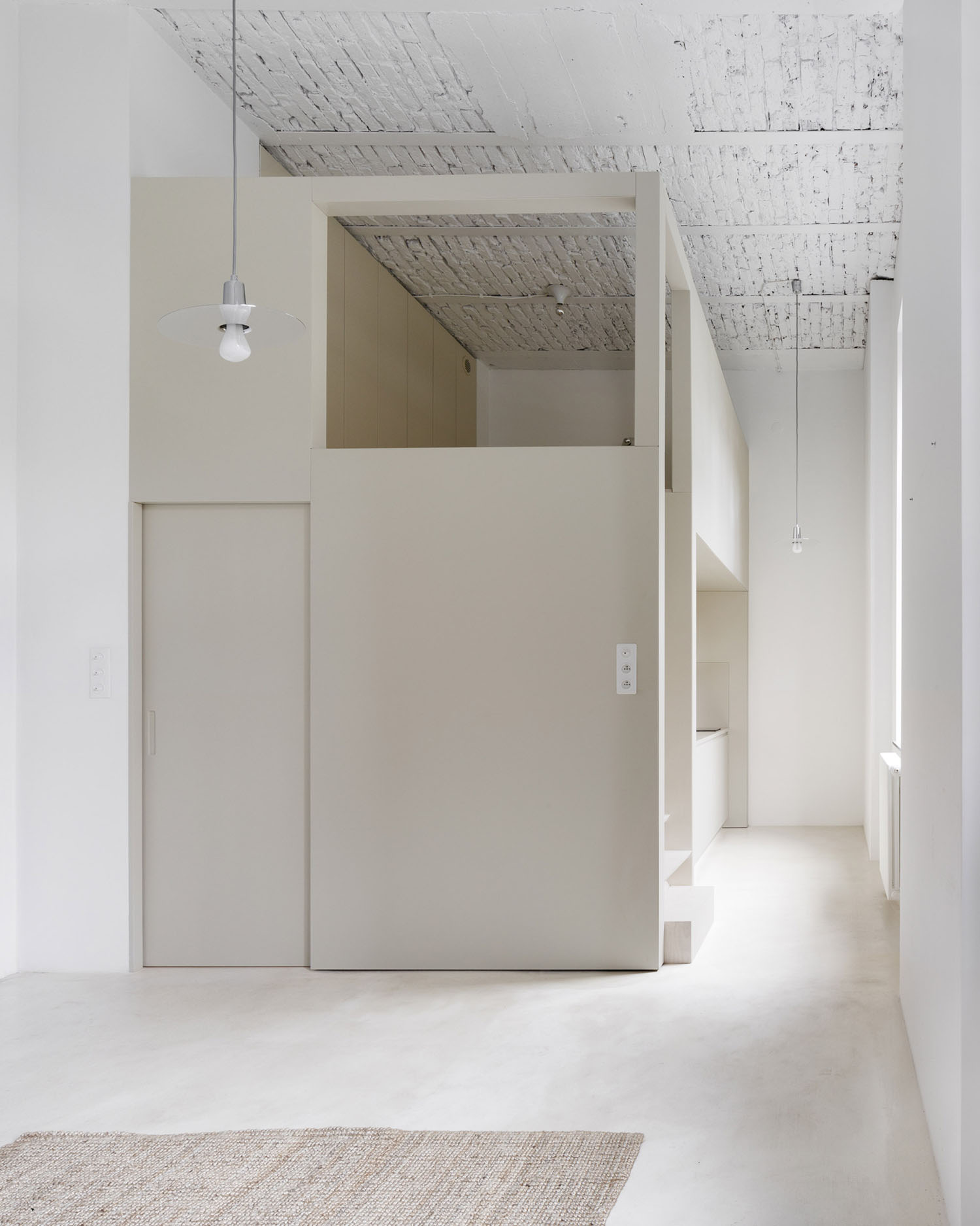 A-PLACE K907 by Thisispaper Studio — A compressed passage beneath a cream-painted plywood mezzanine structure reveals the project's spatial strategy within the historic Print House.