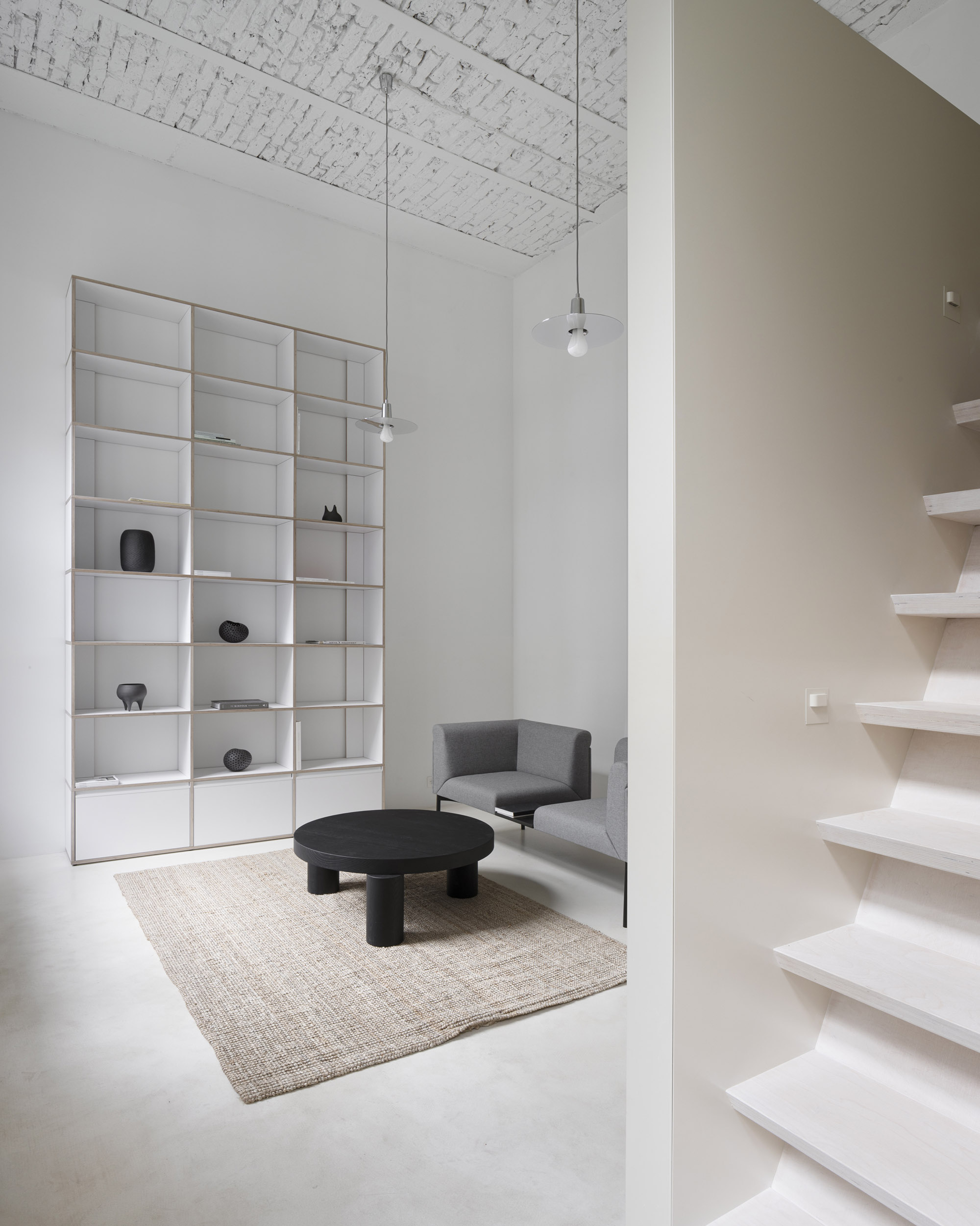 A-PLACE K907 by Thisispaper Studio — A recessed residential alcove within the restored 1903 Print House features a modular white plywood shelving unit with 18 compartments, displaying...