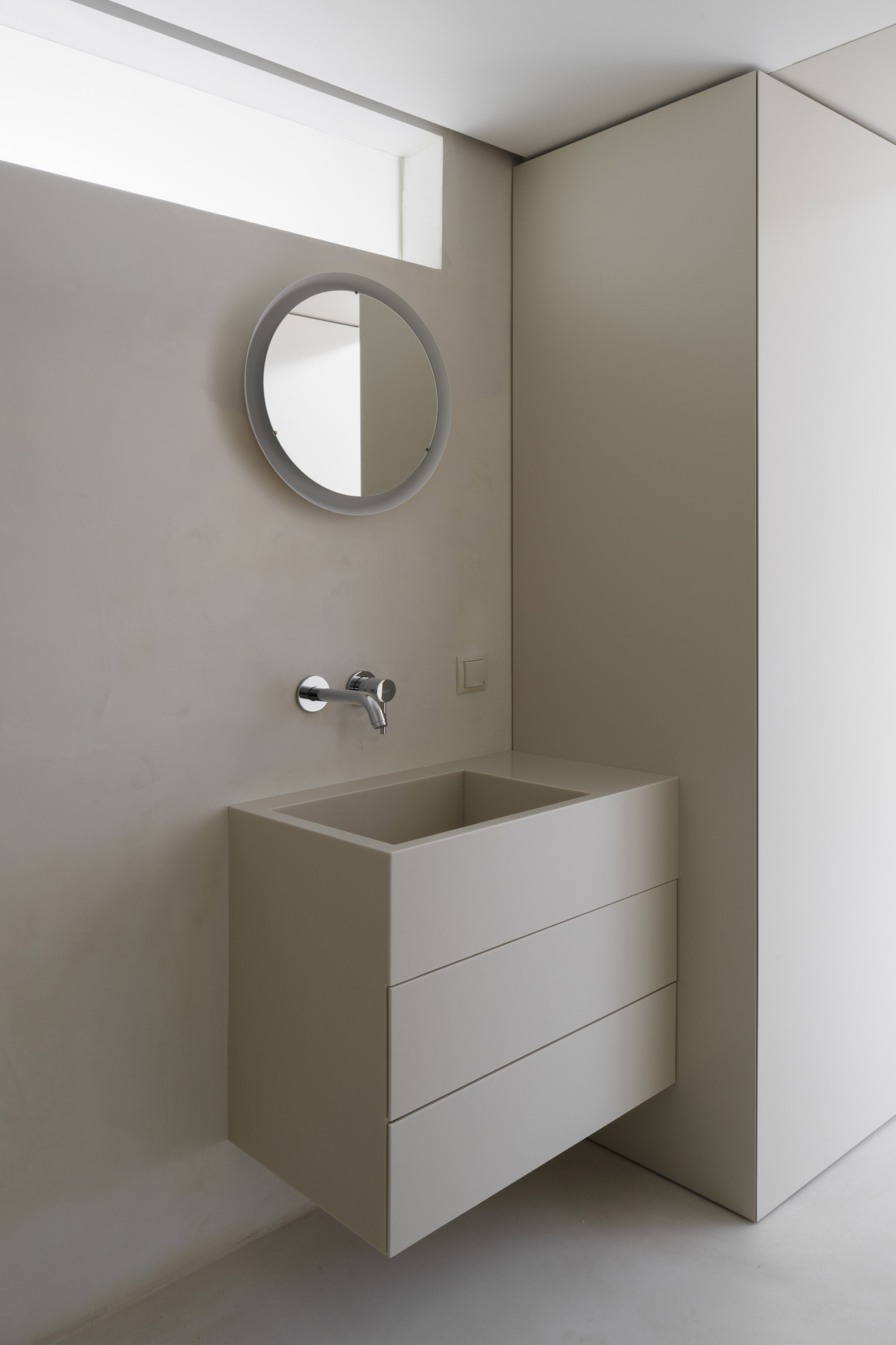 A-PLACE K907 by Thisispaper Studio — A bathroom vanity anchored within a monolithic cream plaster alcove, demonstrating the project's restraint and structural expression.