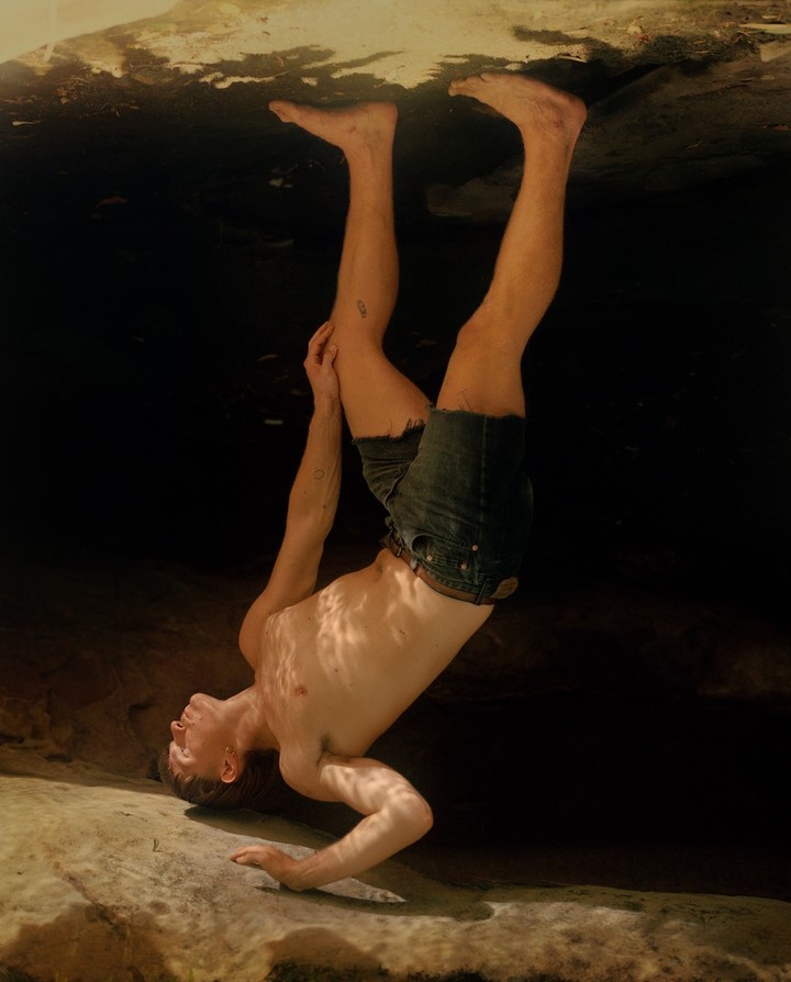 Selected works by András Ladocsi — A man positioned upside-down in shallow water, head submerged to mouth level, creating a disorienting inversion of perspective.
