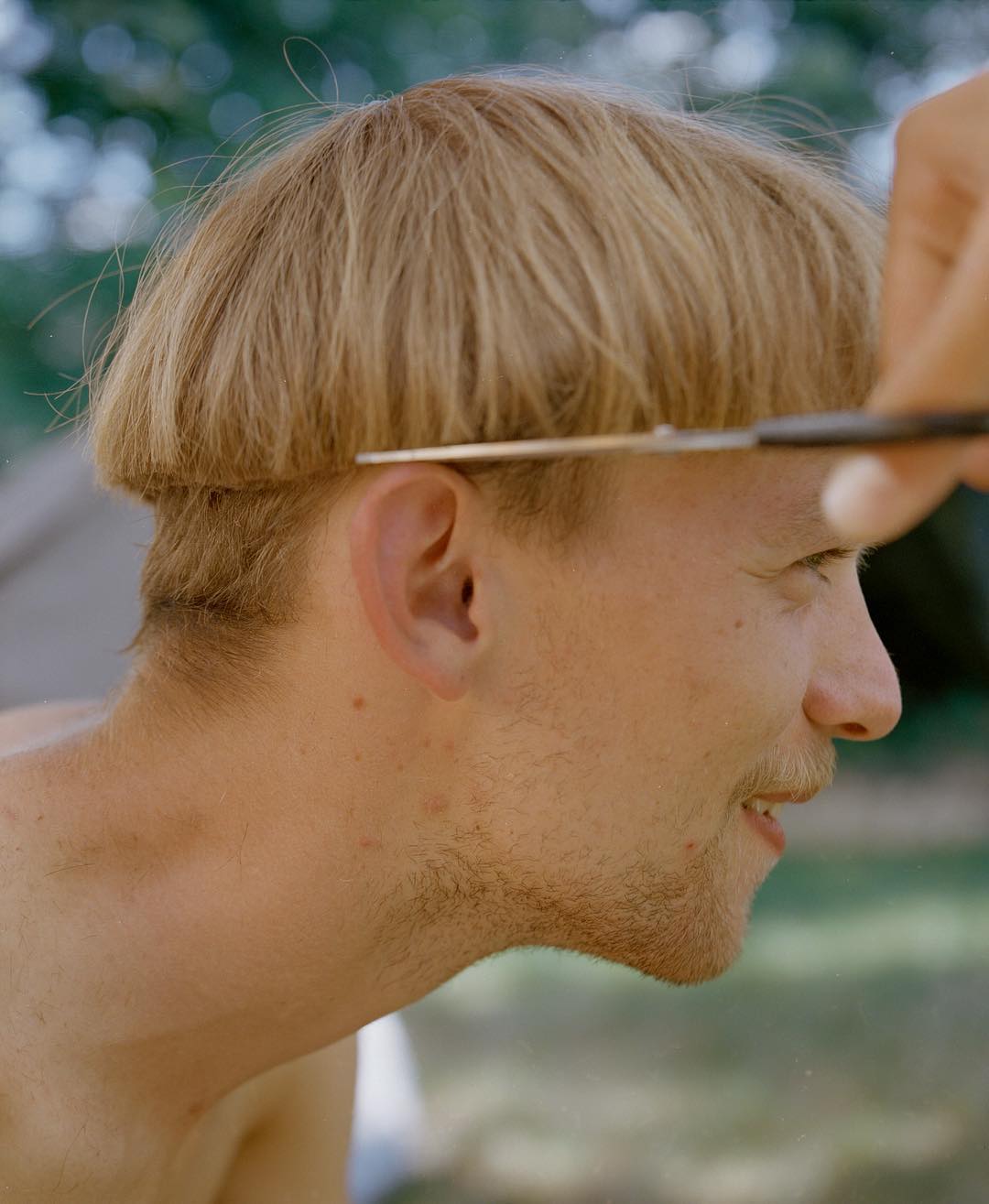 Selected works by András Ladocsi — Profile portrait of a man with blonde hair and facial stubble, head tilted at an angle with direct gaze toward camera.