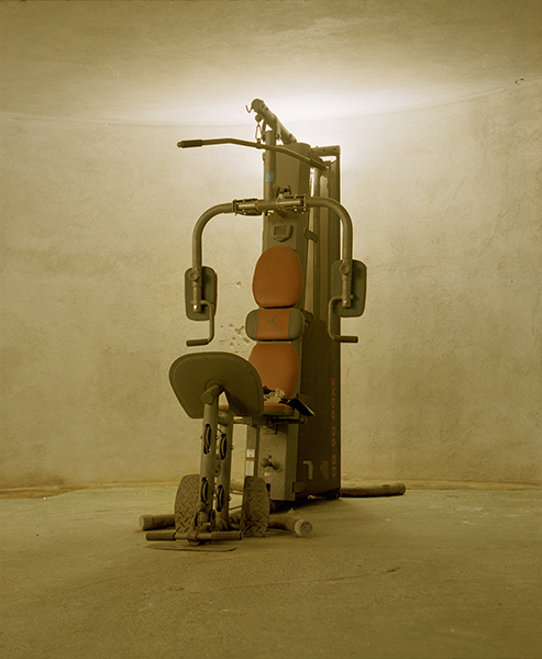 Selected works by András Ladocsi — A stationary exercise machine dominates the composition, photographed frontally against a neutral beige wall.
