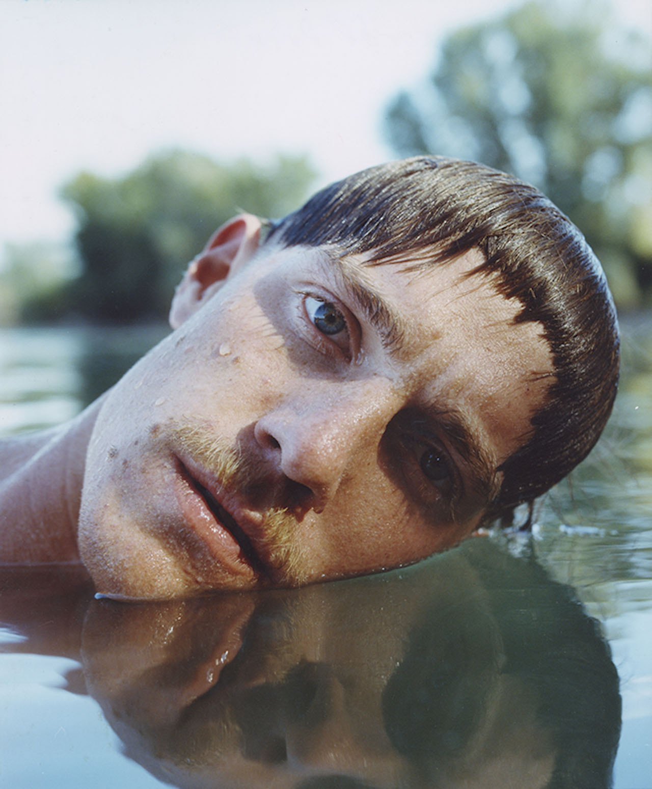 Selected works by András Ladocsi — A man's head emerges from dark water, tilted at an acute angle with direct eye contact toward the camera.