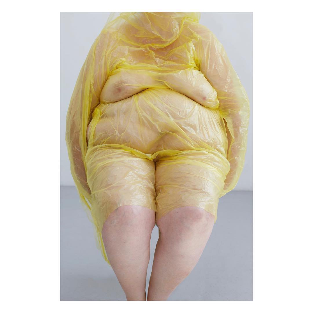Selected works by Polly Penrose — A figure wrapped in translucent yellow plastic sheeting stands against a neutral background.